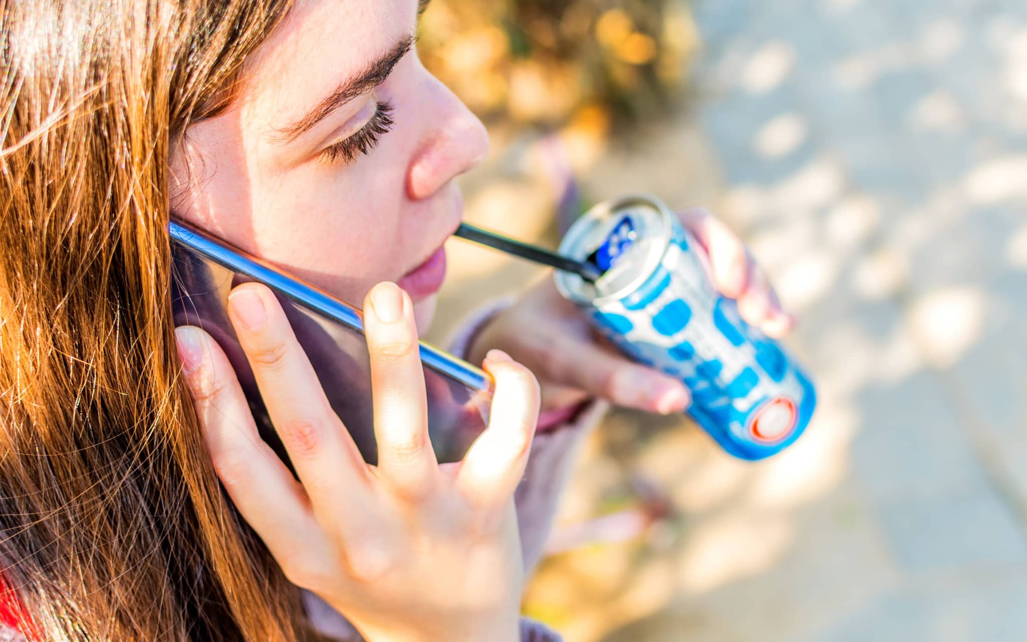 Energydrink: Ein Mädchen hält einen Energie Drink mit Strohlhalm in der Hand