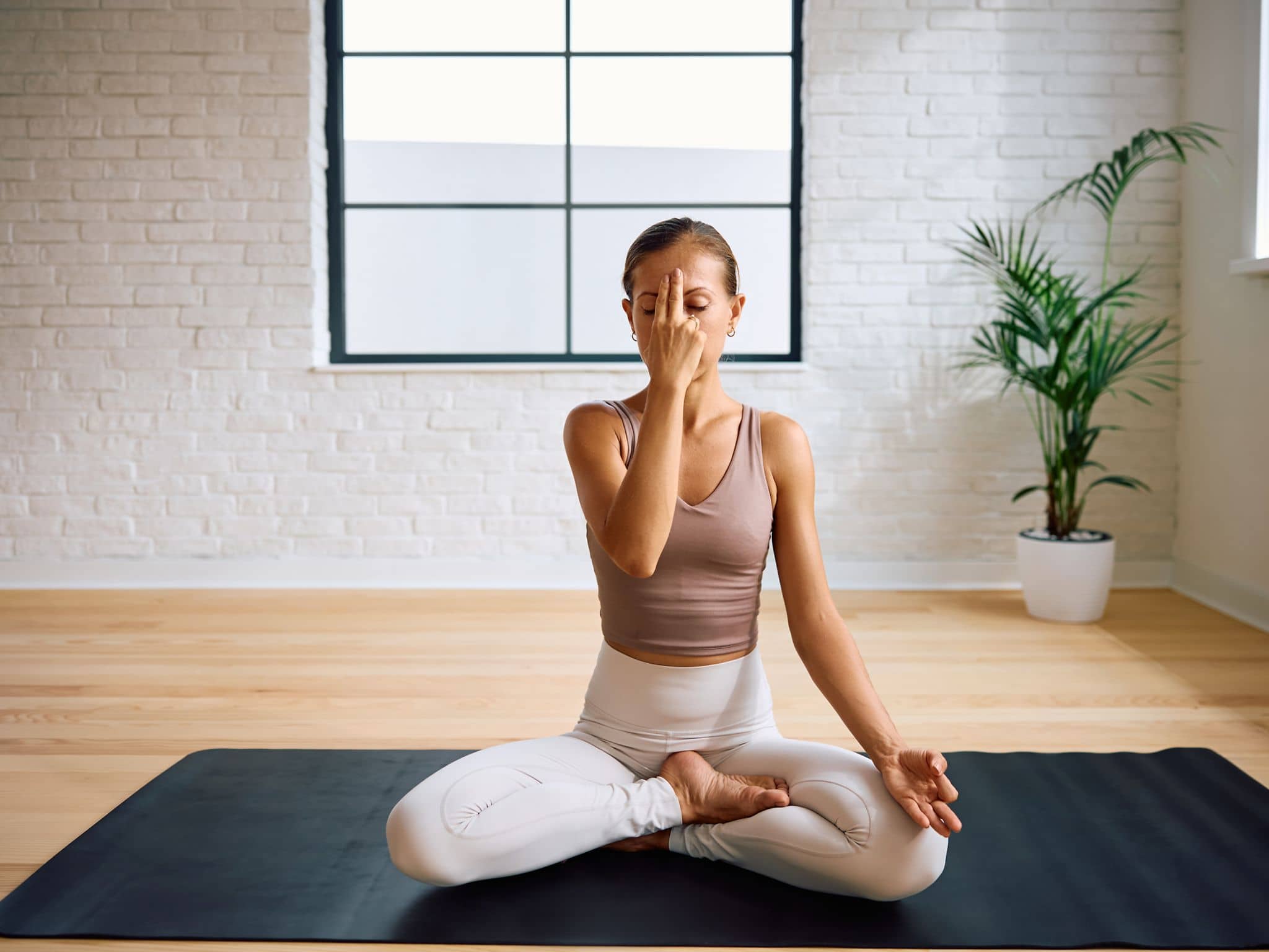 Pranayama: Eine Frau sitzt im Schneidersitz und praktiziert die Wechselatmung