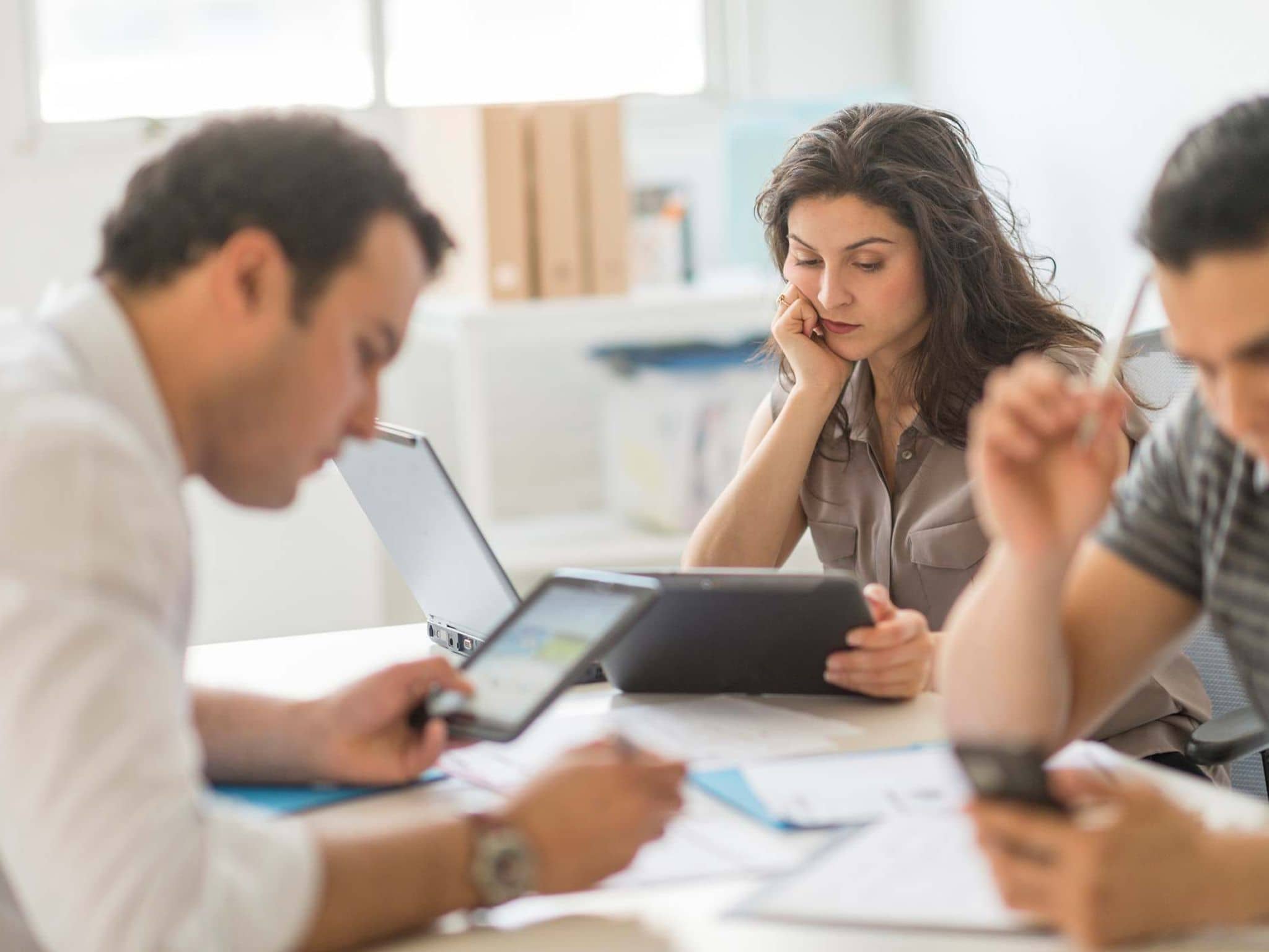 Team arbeitet konzentriert an PCs, Tablets und Handy.