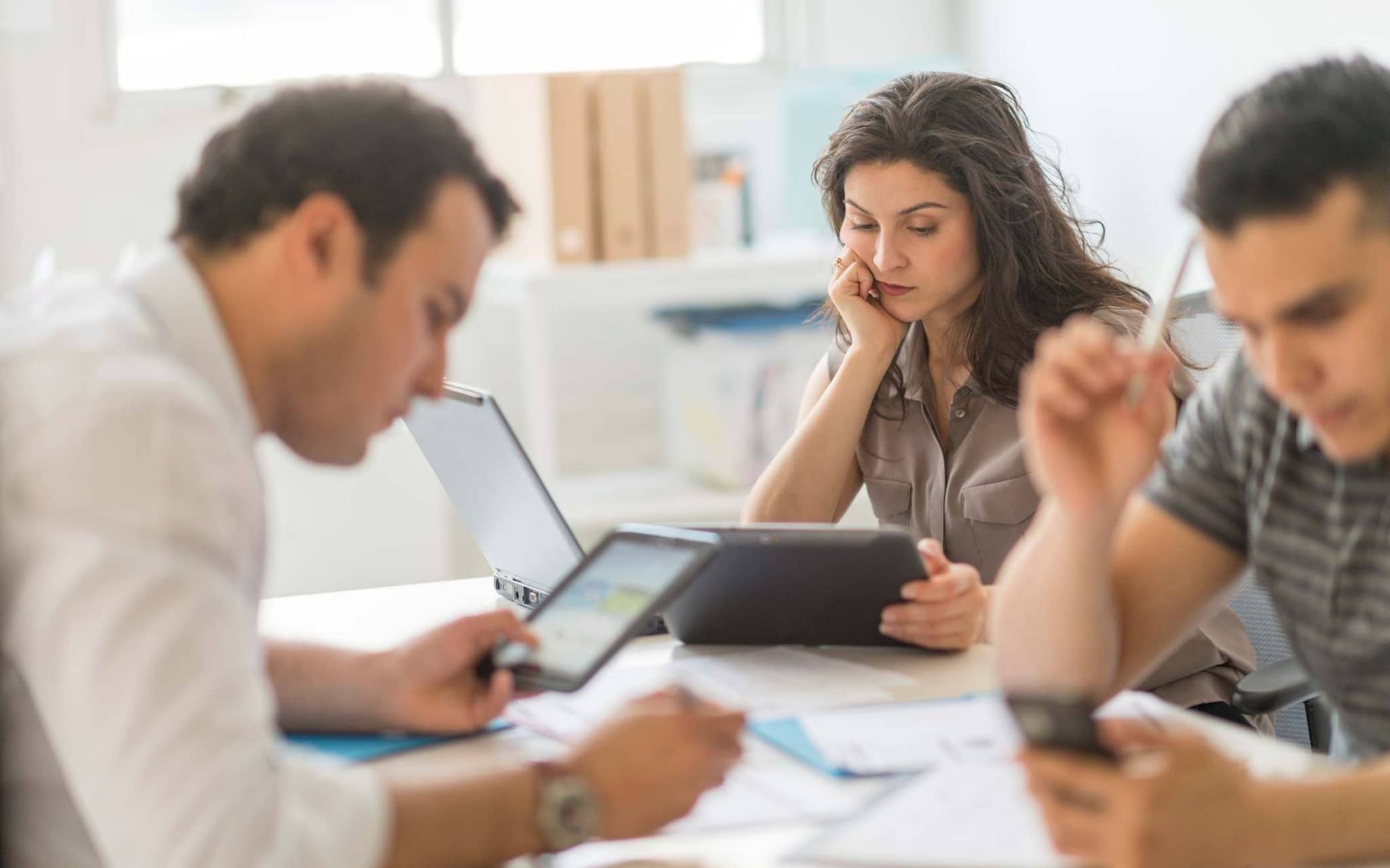 Team arbeitet konzentriert an PCs, Tablets und Handy.