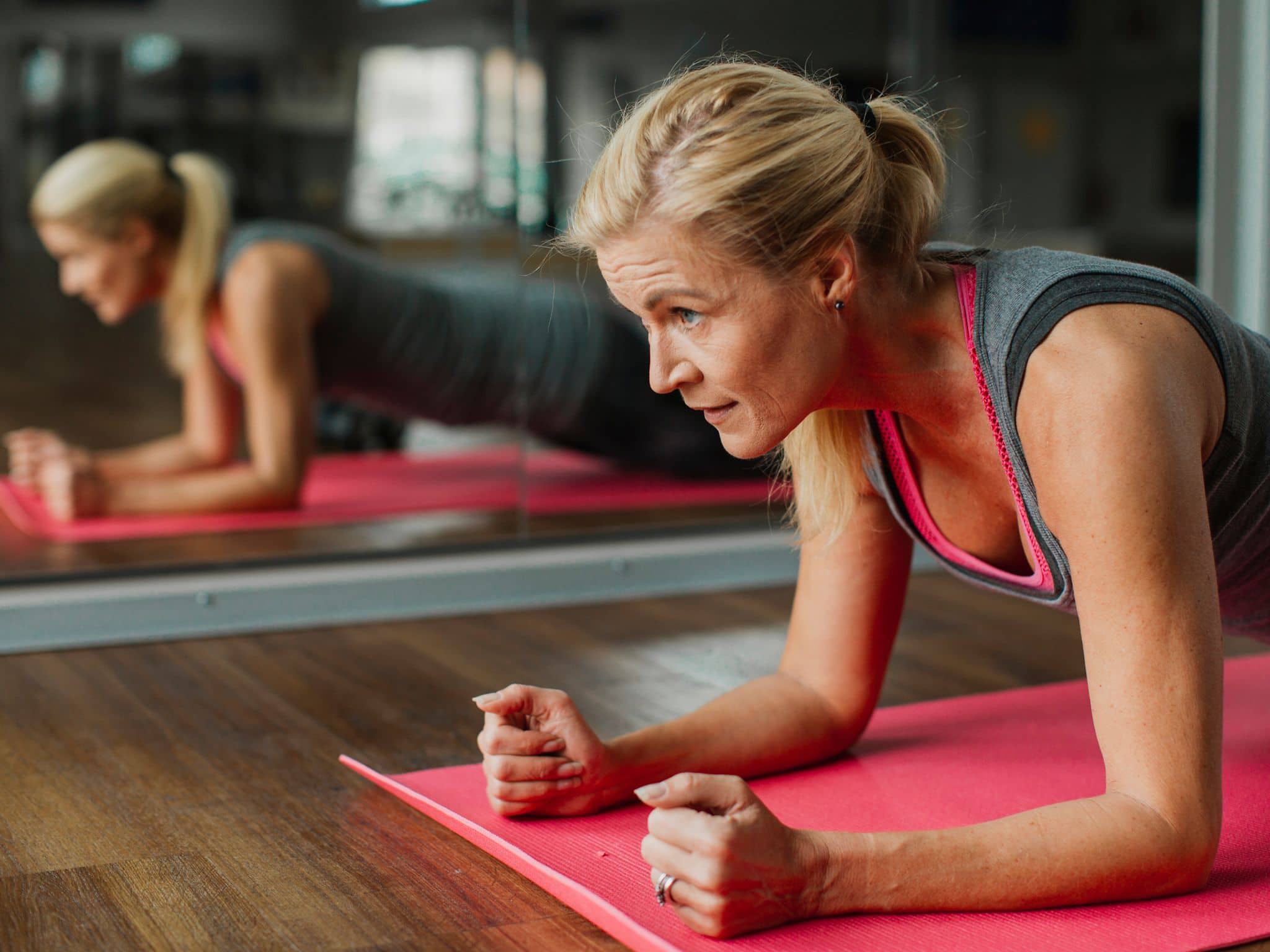 Muskelaufbau im Alter: Eine Frau im mittleren Alter macht eine Plank beim Krafttraining