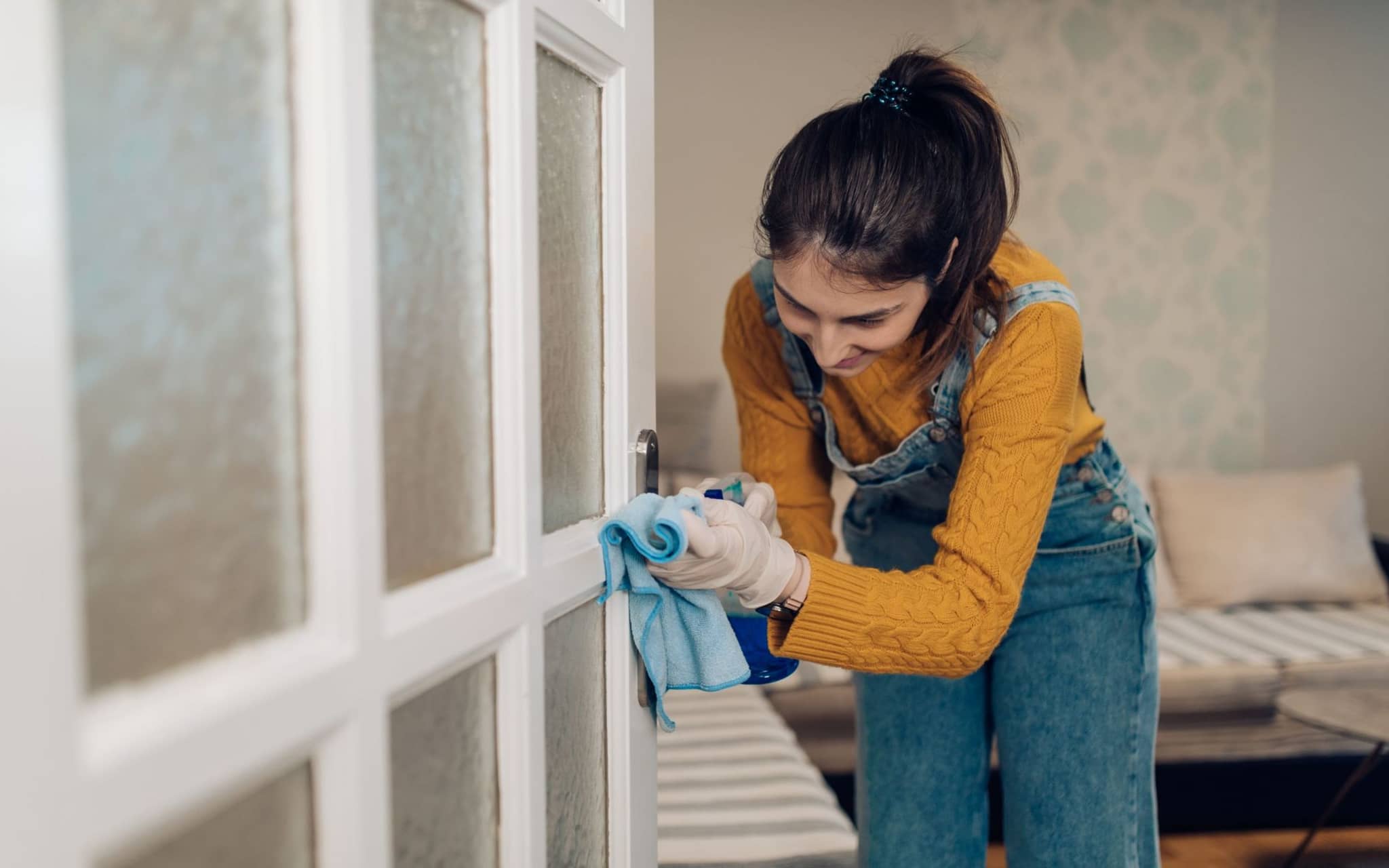 Eine Frau macht eine Türklinke sauber, um einer Erkältung vorzubeugen.