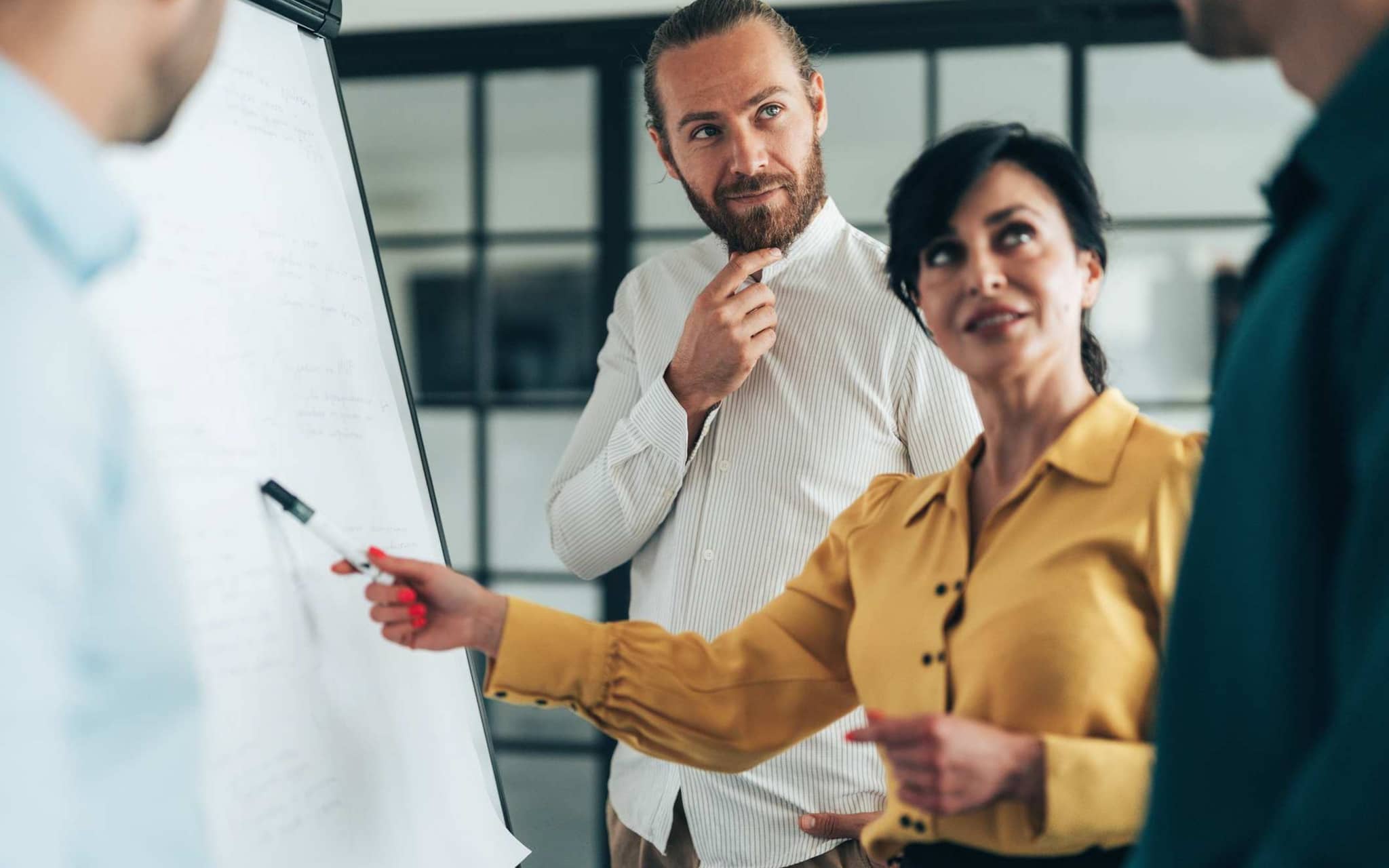 Frau vor Flipchart in Diskussion mit Kollegen