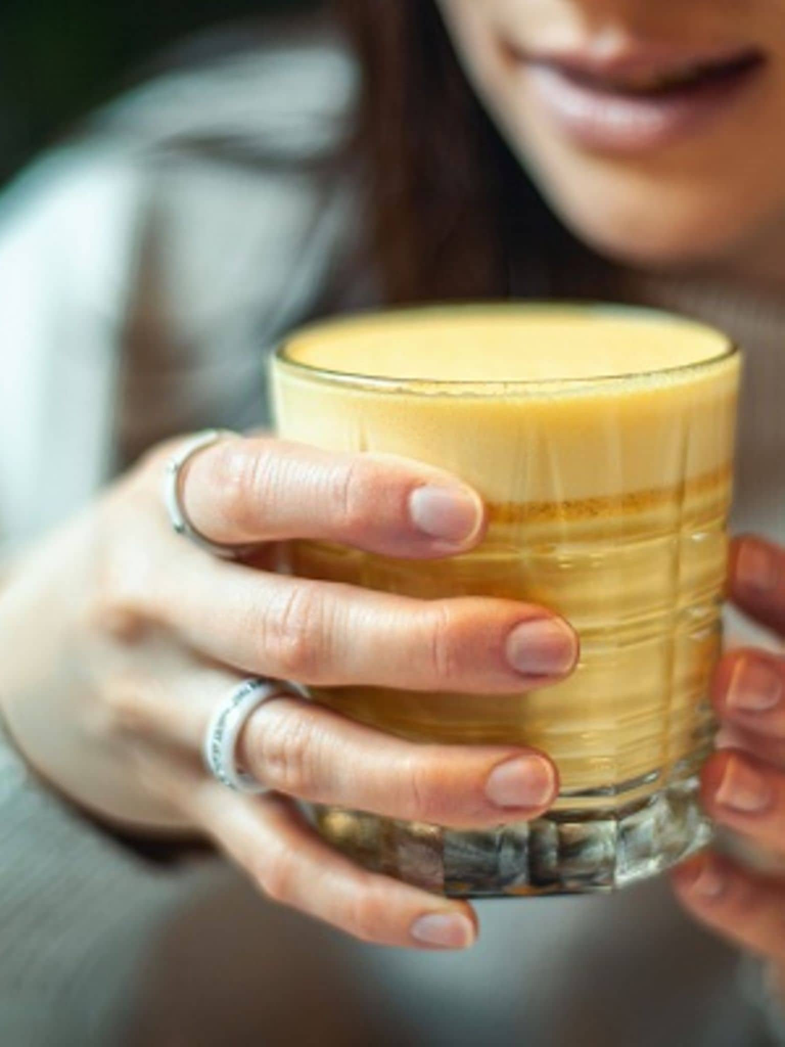 Eine Frau hält ein Glas goldene Milch in der Hand