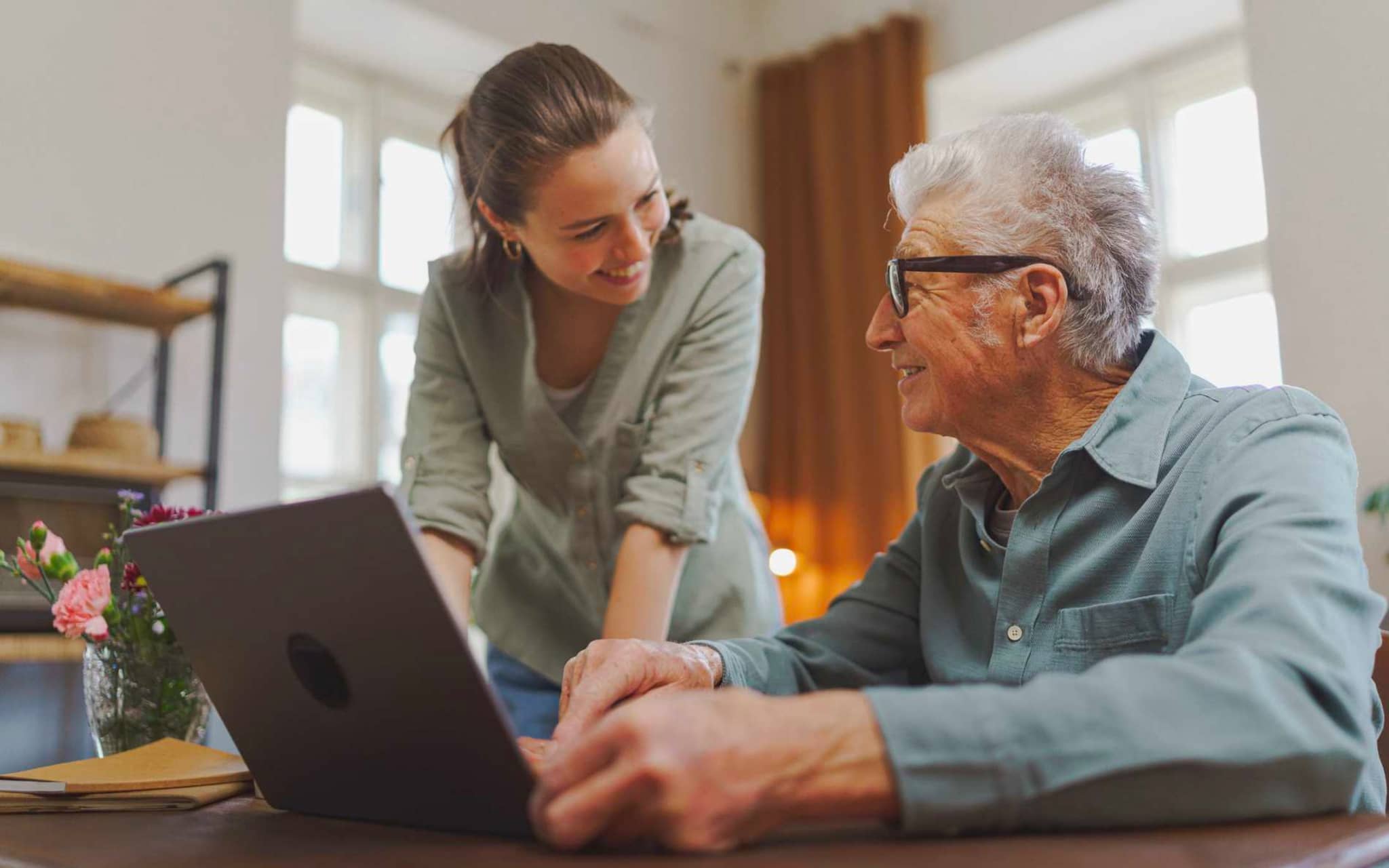 Bild: Angehörige zeigt ihrem älteren Vater etwas am Laptop