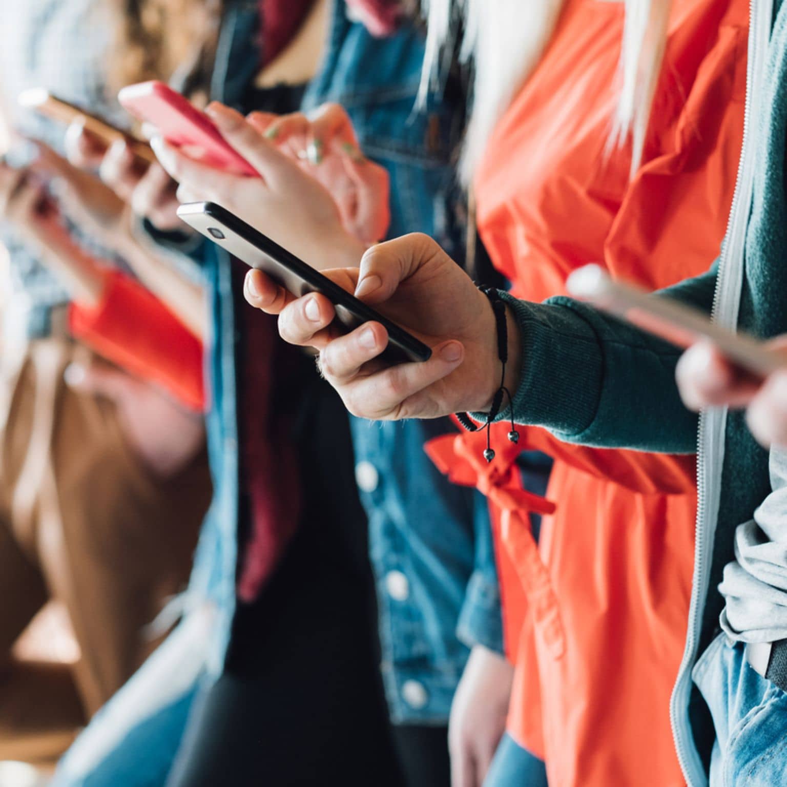 Mehrere Personen stehen nebeneinander und benutzen ihre Smartphones.