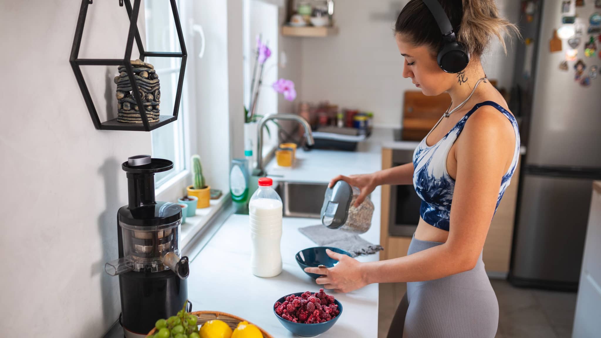 Sportliche junge Frau bereitet sich ein Müsli in der Küche zu