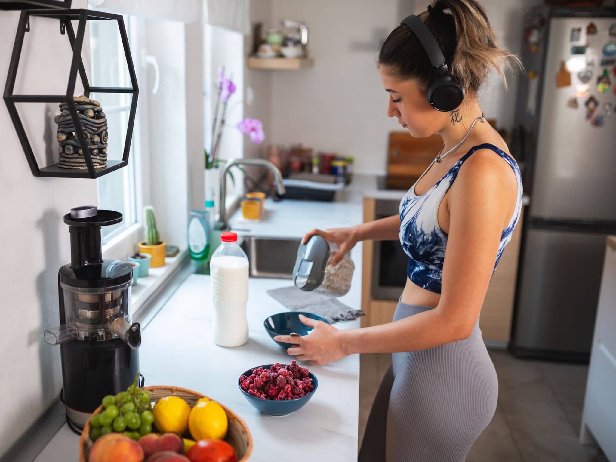 Sportliche junge Frau bereitet sich ein Müsli in der Küche zu