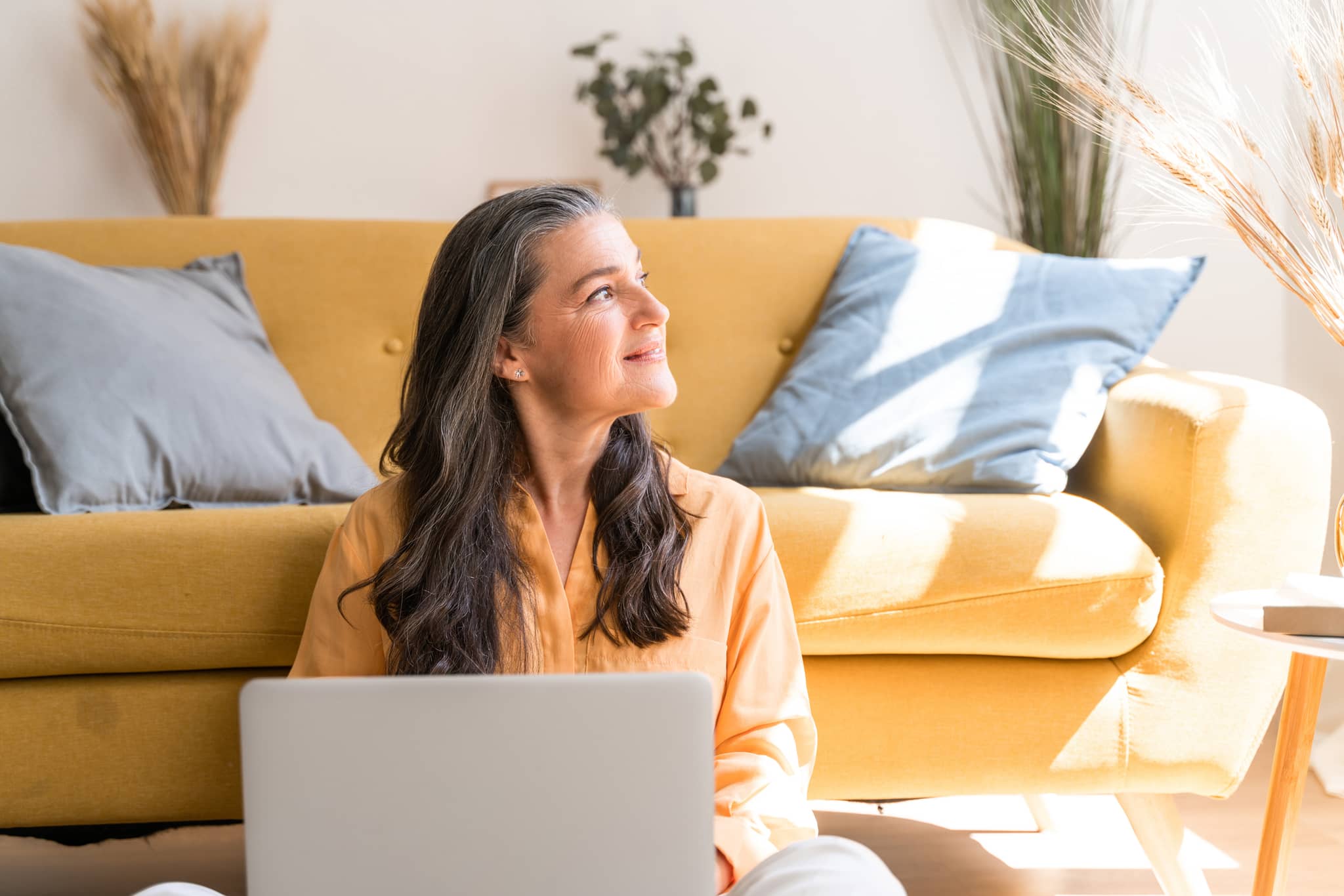DAK Garantietraif 120: Frau sitzt happy vorm Sofa am Notebook