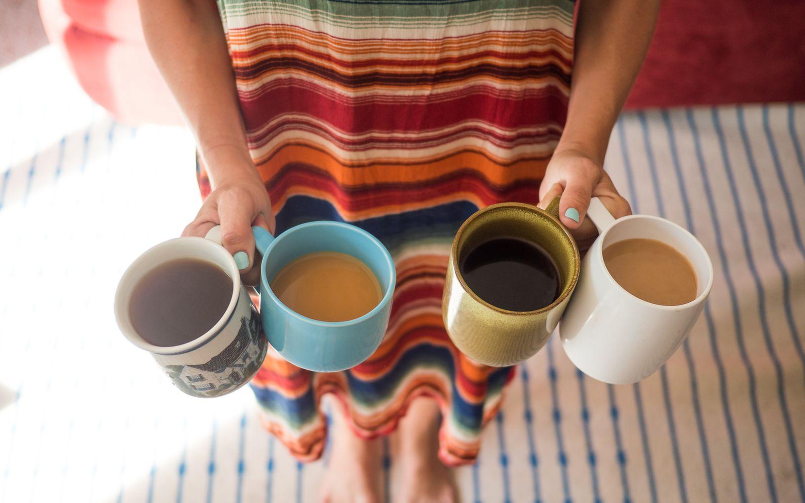 Koffein: Frau hält vier verschiedene Tassen Kaffee in den Händen
