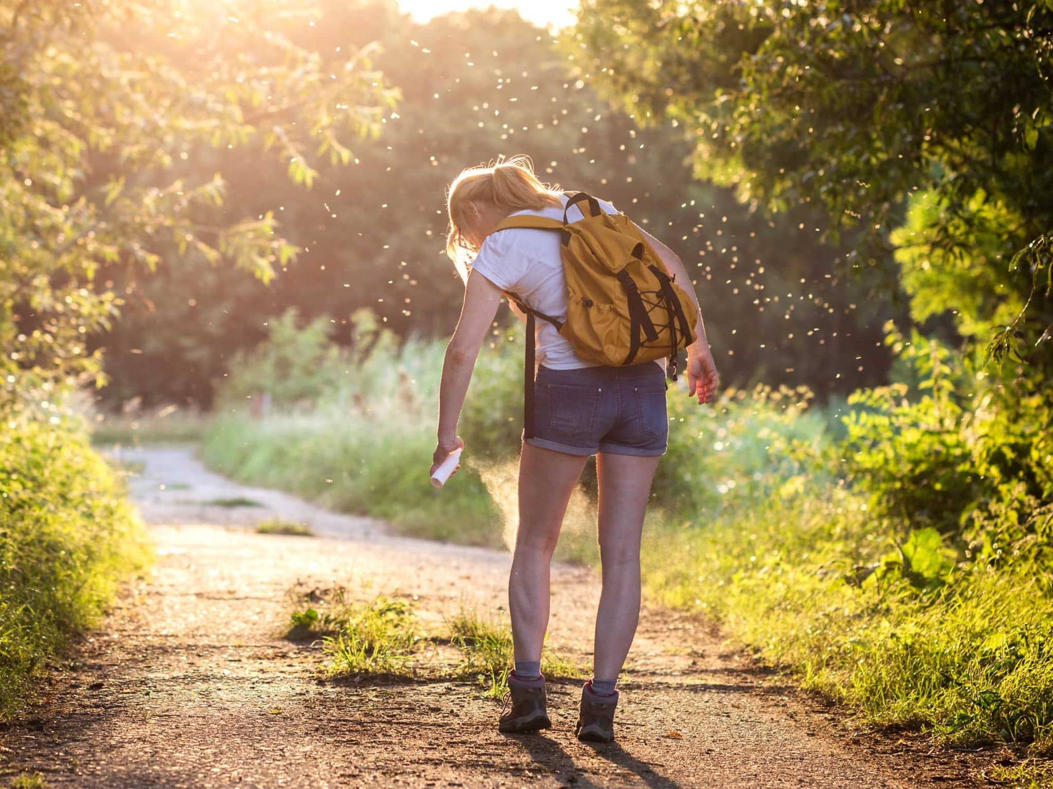 Frau mit Rucksack und Insektenschutzmittel