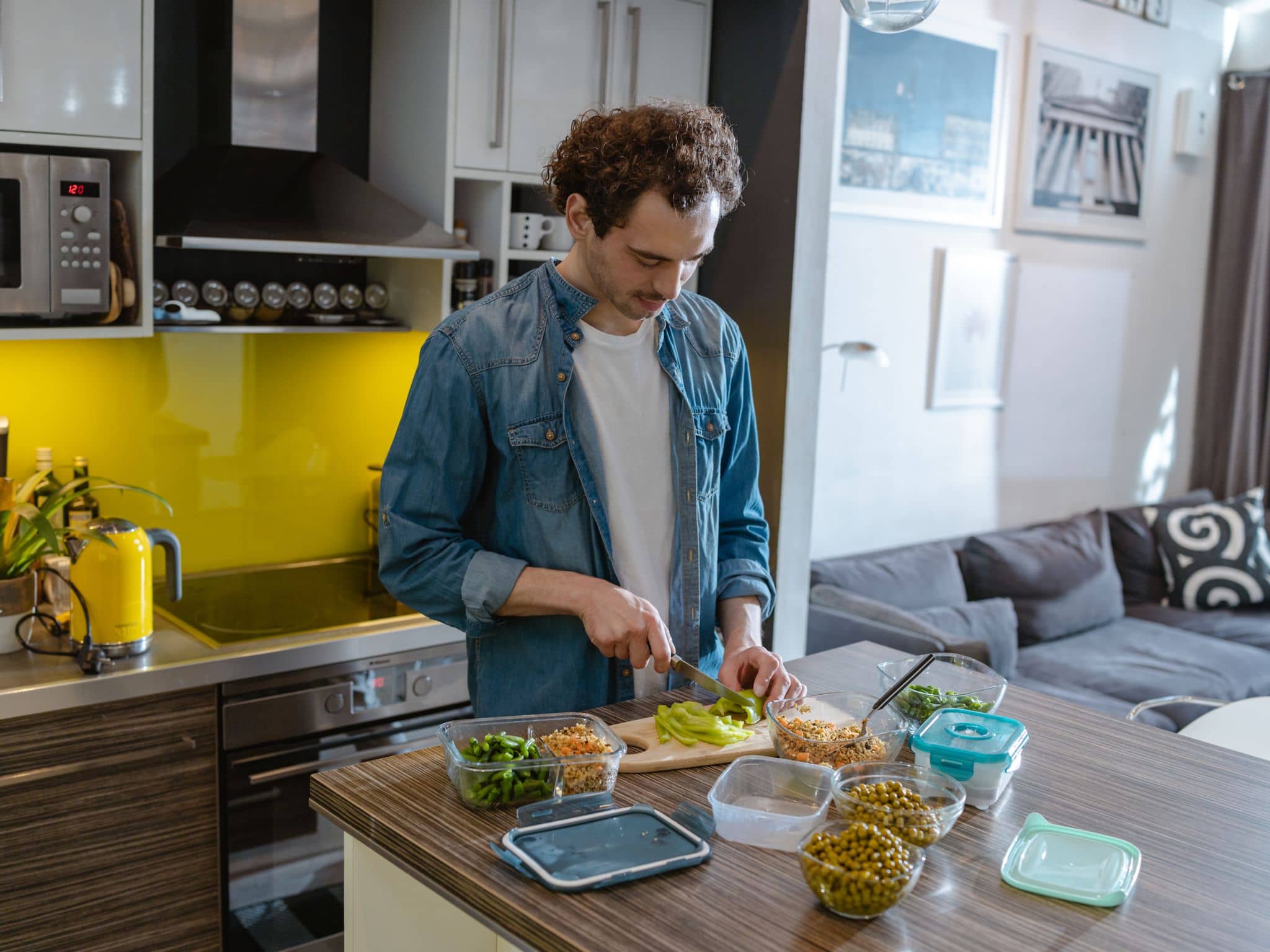 Ein junger Mann steht in der Küche und bereitet sich eine darmgesunde Mahlzeit zu.