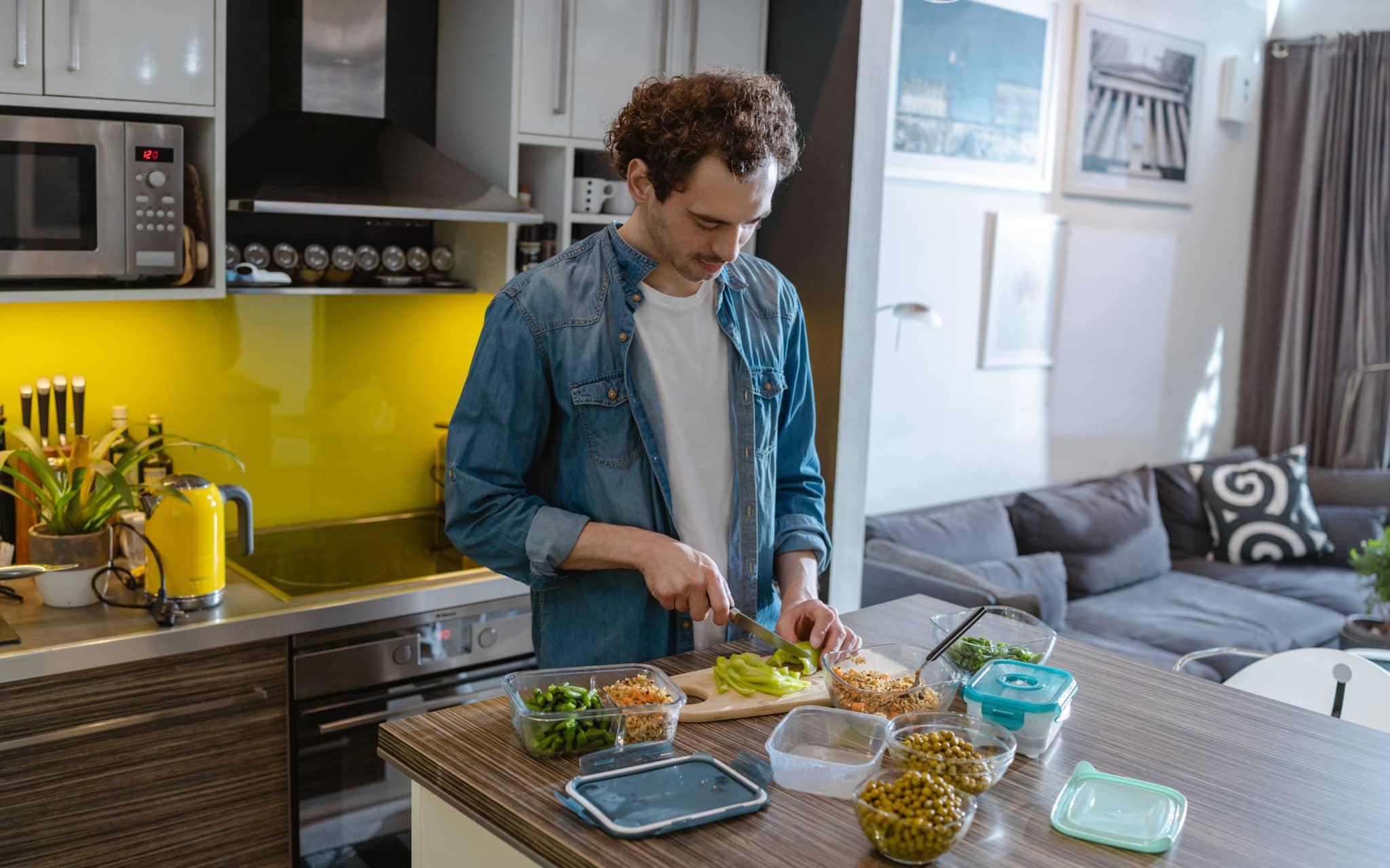 Ein junger Mann steht in der Küche und bereitet sich eine darmgesunde Mahlzeit zu.