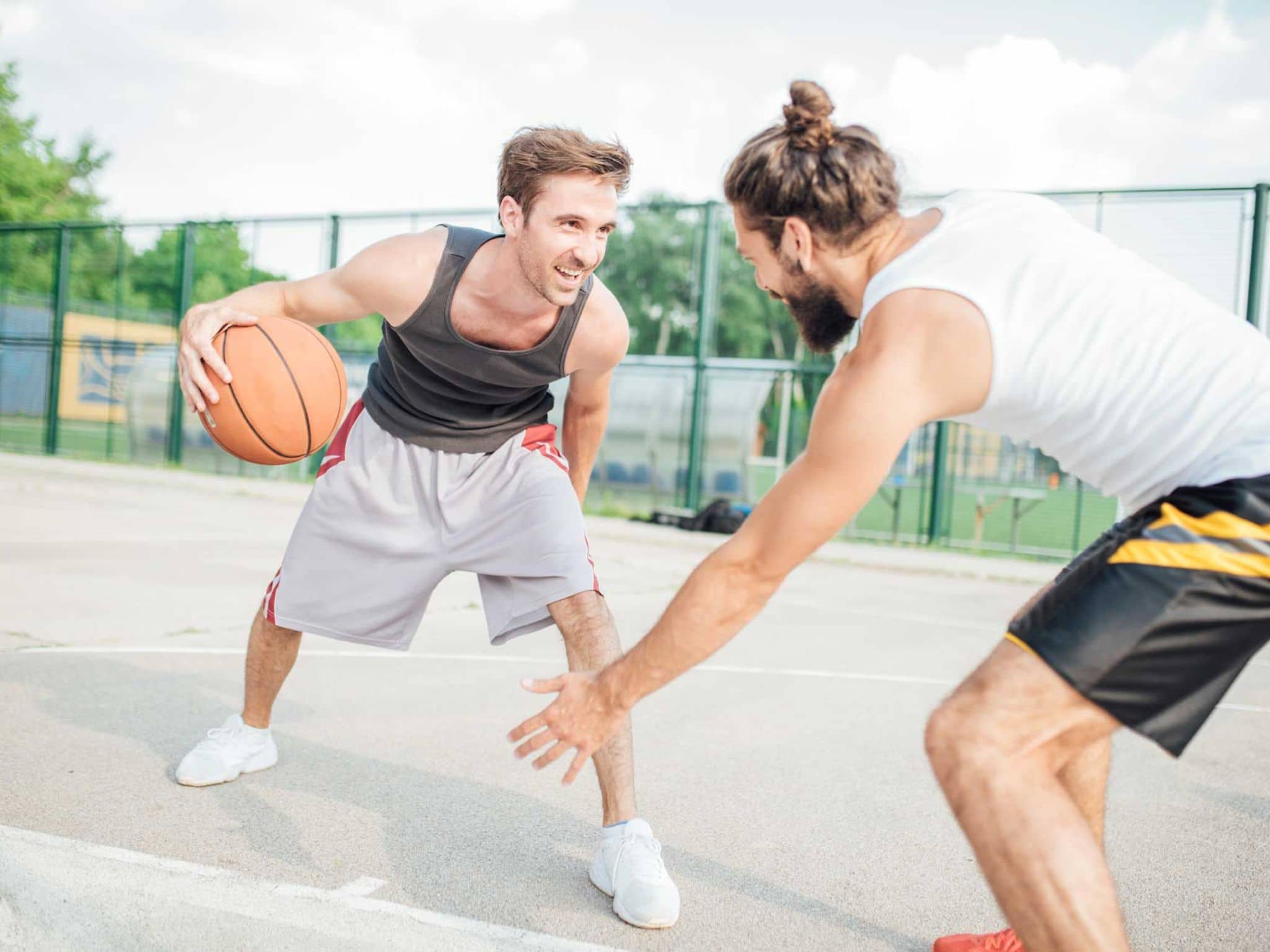 Zwei junge Männer spielen draußen Basketball