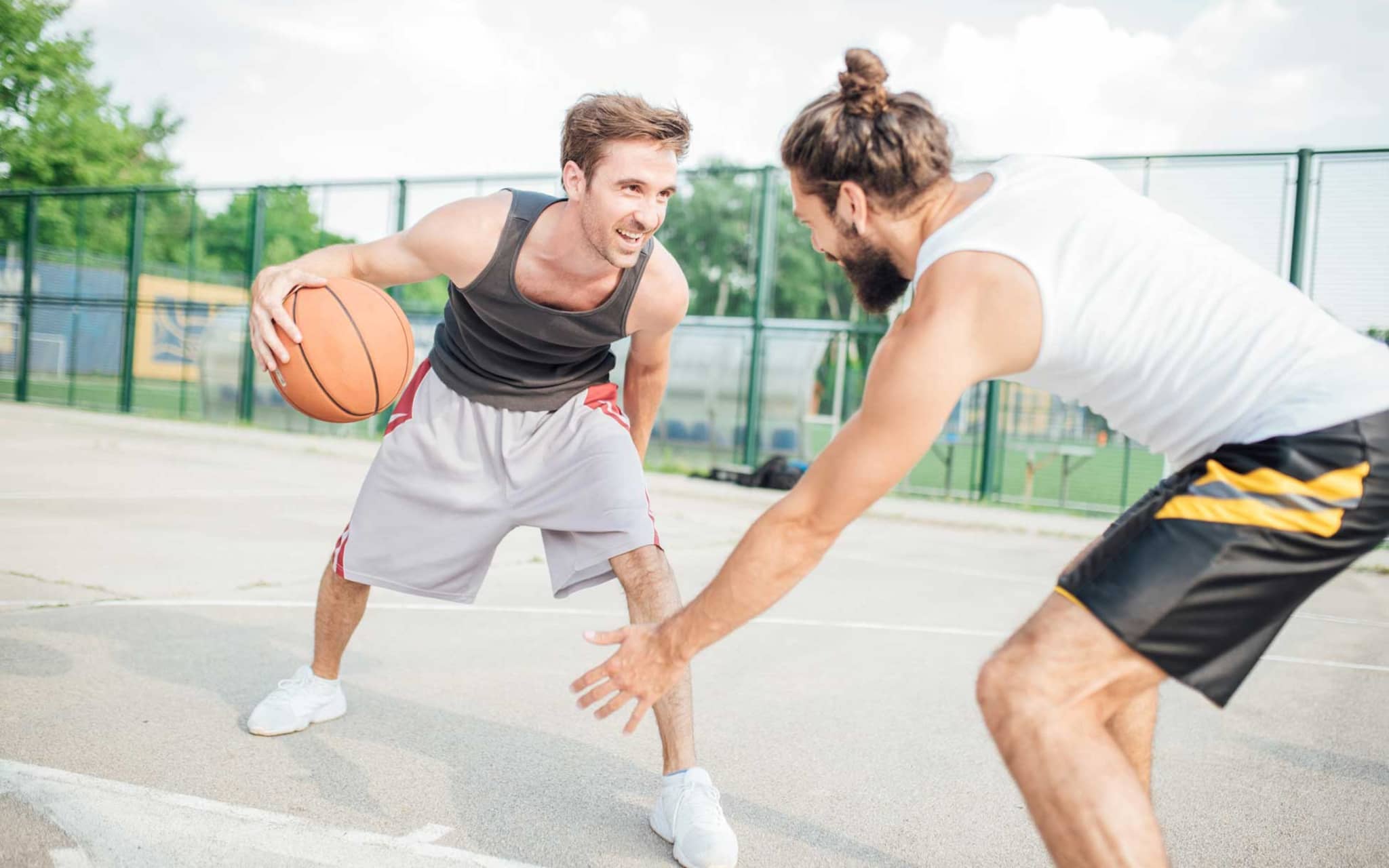 Zwei junge Männer spielen draußen Basketball