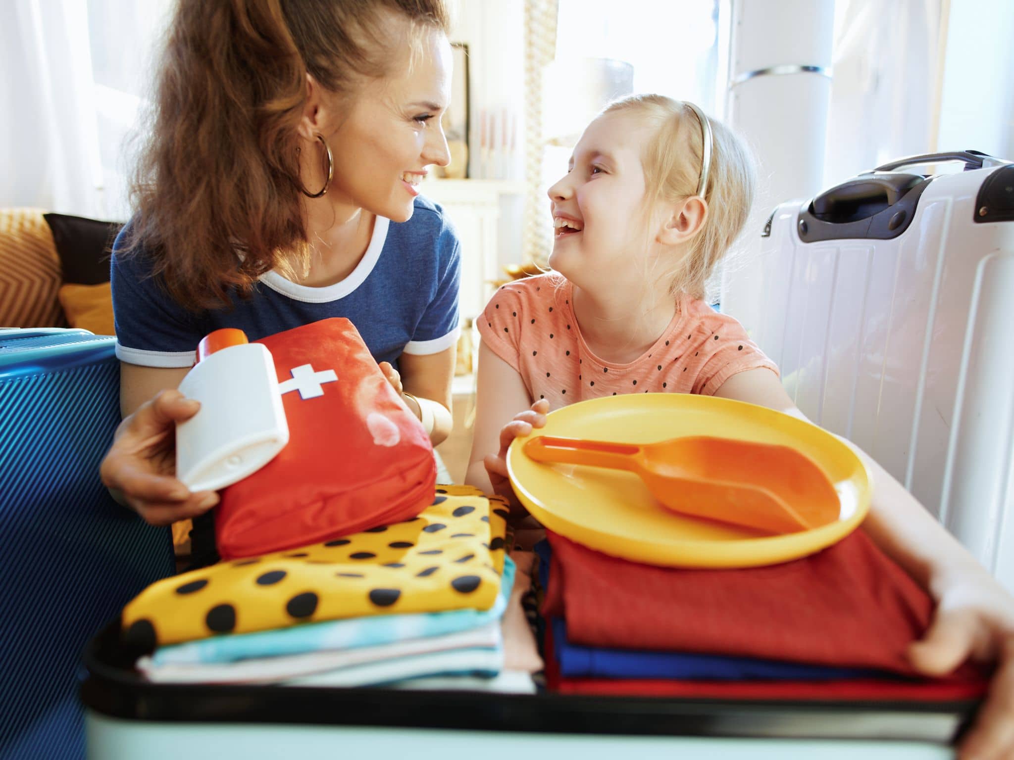 Eine Mutter packt gemeinsam mit ihrer Tochter einen Koffer für den Urlaub.