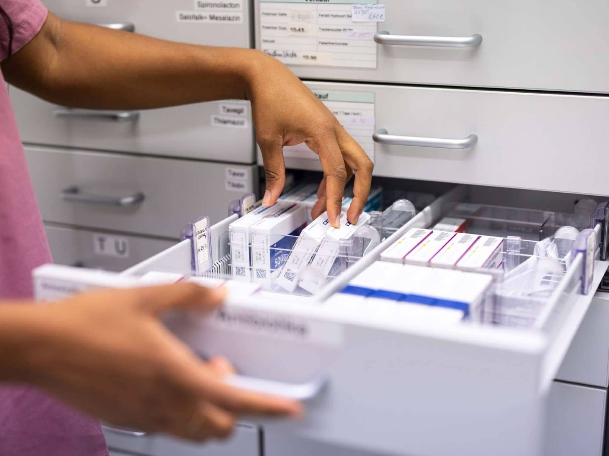 Biosimilars: Hände sortieren Medikamente in Schublade.