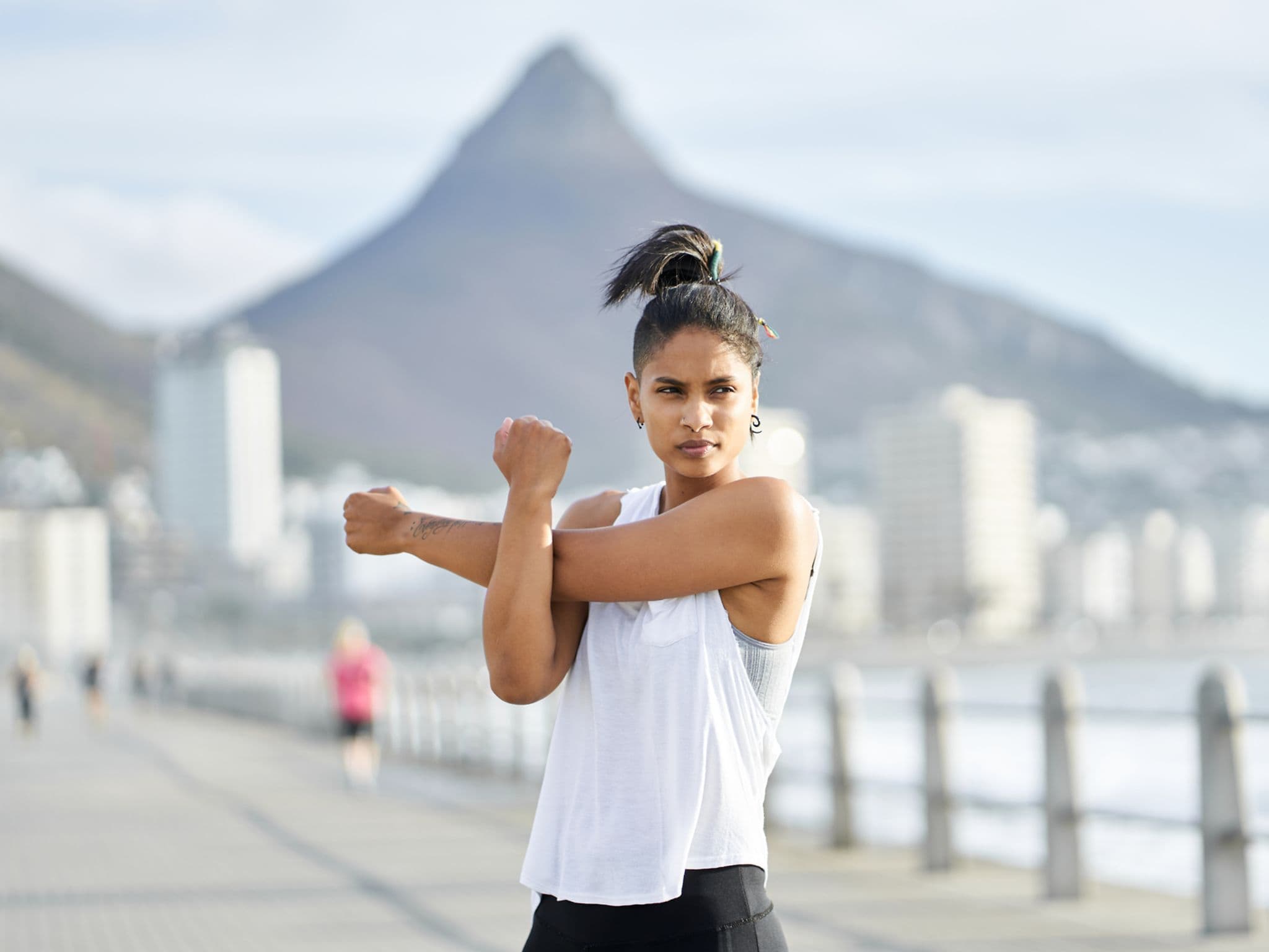 Eine junge Frau dehnt sich während eines Workouts auf einem städtischen Gehweg
