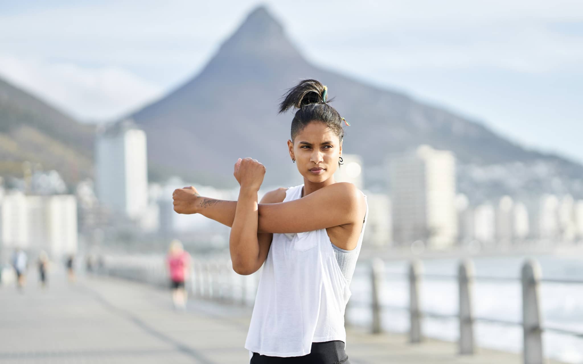 Eine junge Frau dehnt sich während eines Workouts auf einem städtischen Gehweg
