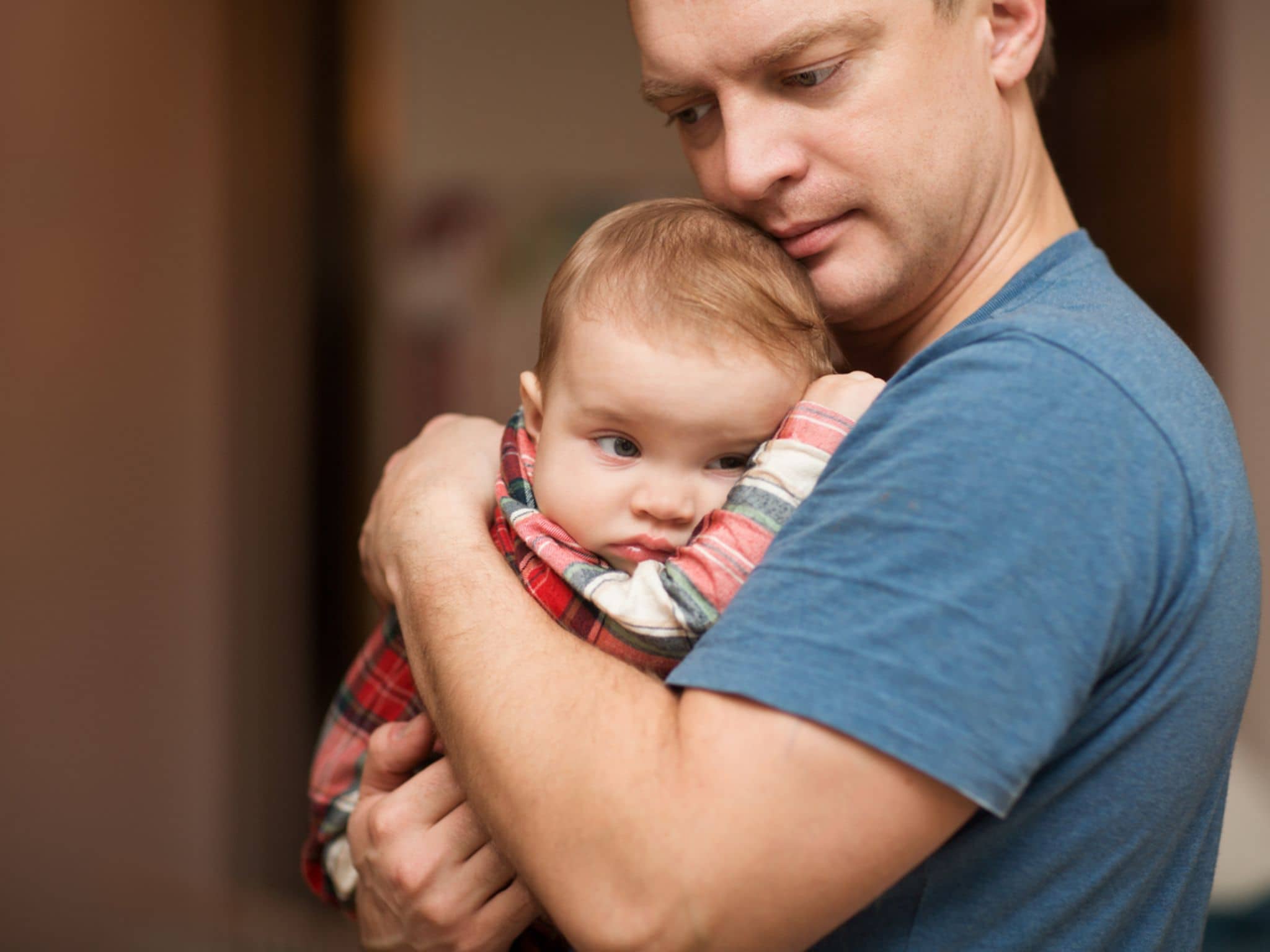 Der Vater hält auf den Händen der traurige Baby. Familien-Konzept. Auf die Milchzähne werden geschnitten.