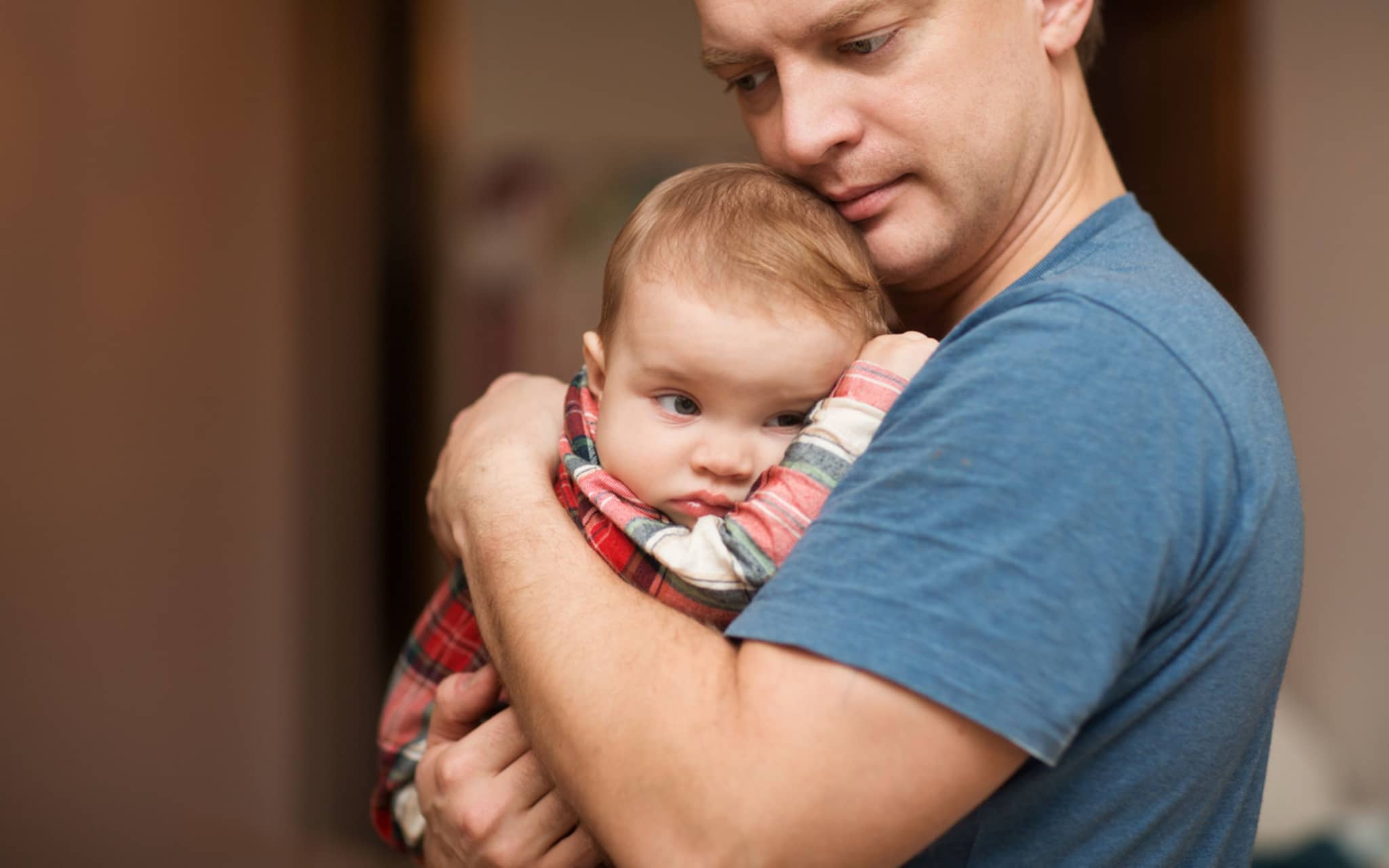 Der Vater hält auf den Händen der traurige Baby. Familien-Konzept. Auf die Milchzähne werden geschnitten.