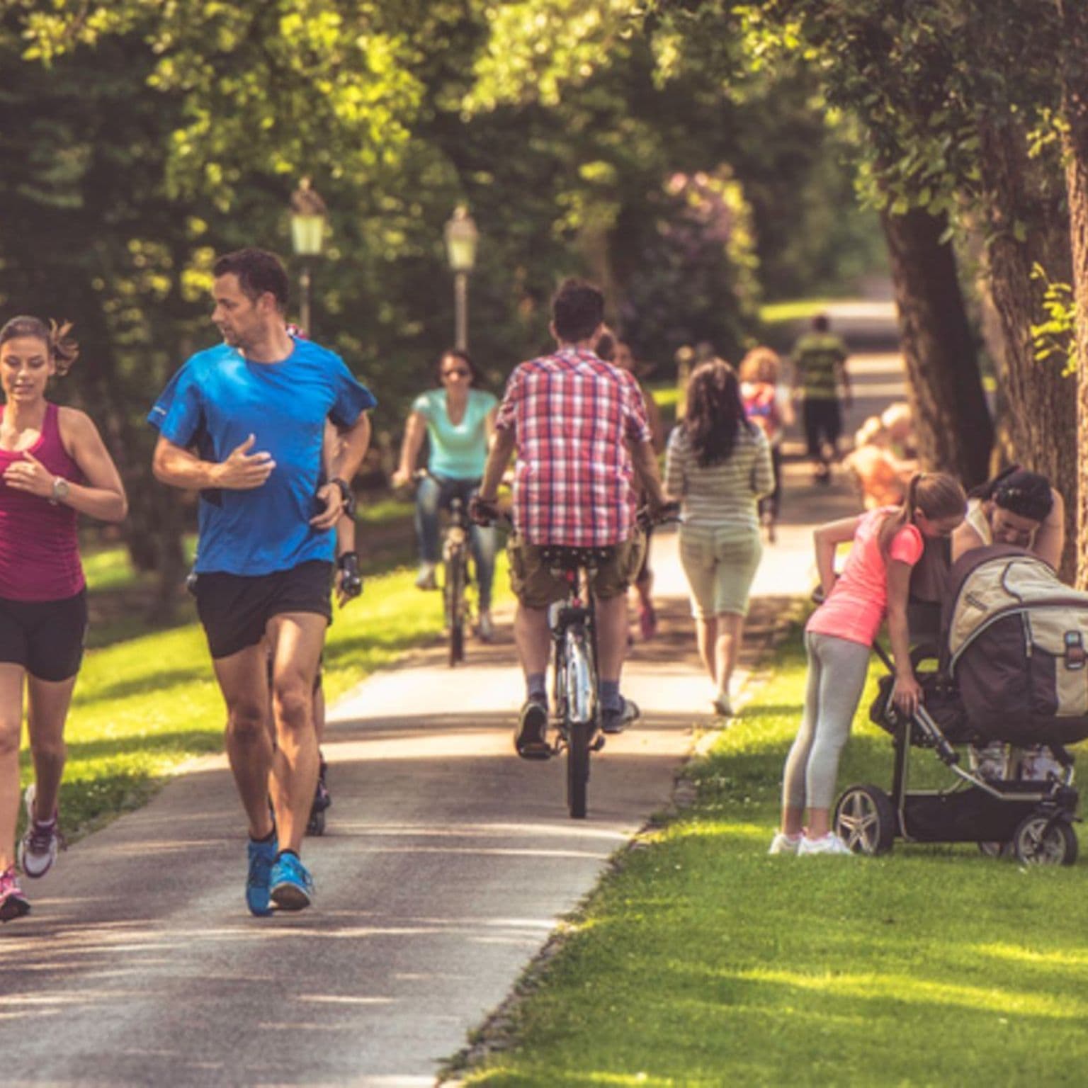 Sport und Gesundheit: Paar joggt an einem sonnigen Tag durch einen belebten Park.