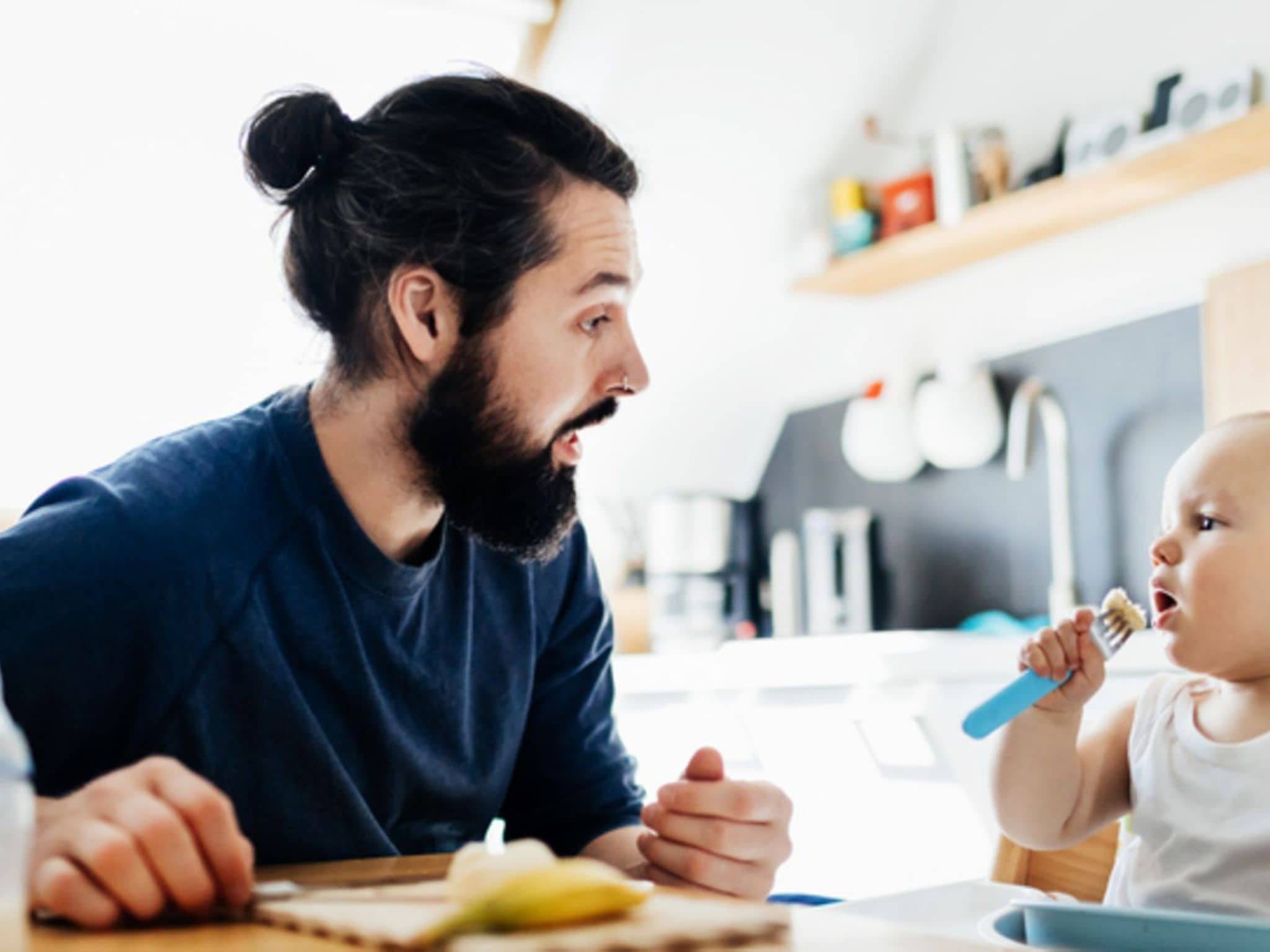 Gesunder Ernährung Kinder: Ein Vater bereitet seinem kleinen Kind eine Banane zum Essen vor.