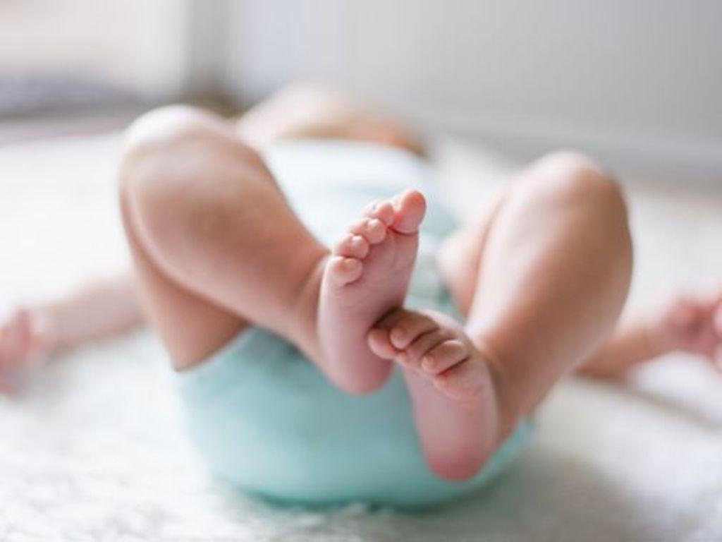 Symbolbild Babypflege: Ein Baby streckt seine Füße in die Luft, Ansicht von unten