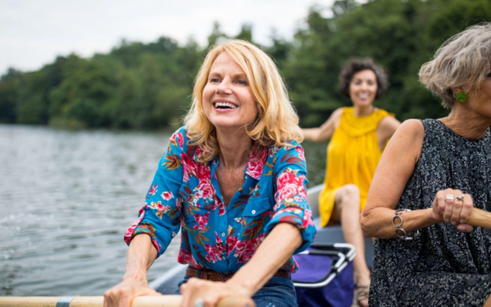 Lächelnde Frau mit Freund-Ruderboot in See