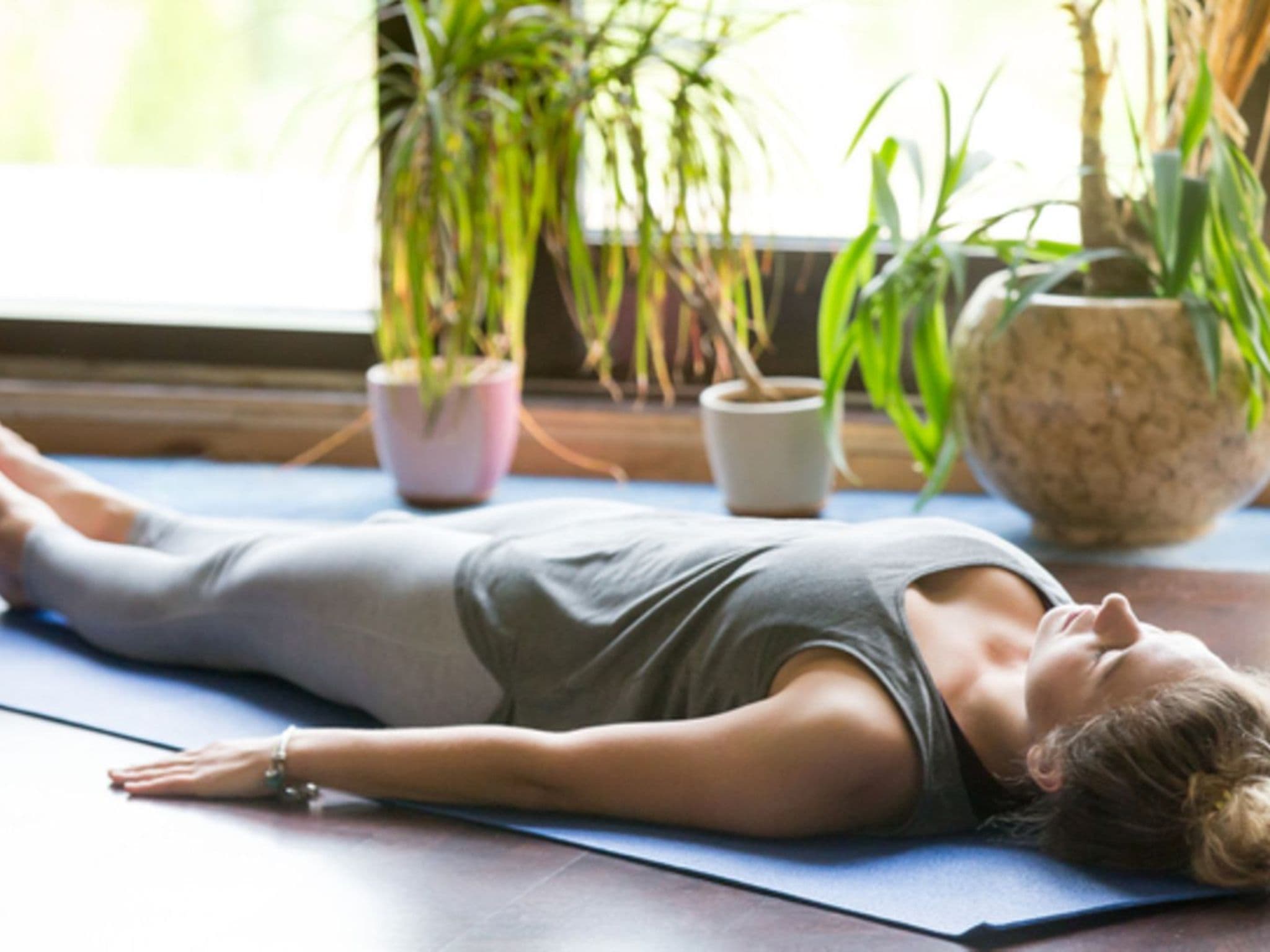 Meditation: Eine Frau liegt entspannt auf dem Fußboden und meditiert.