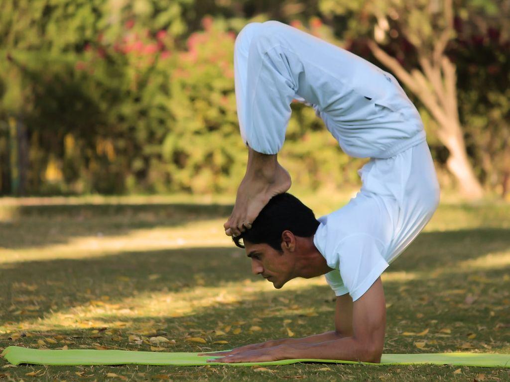 Yoga für Männer: Indian Yogi (Yogi Madhav) macht Yoga in einem Park.