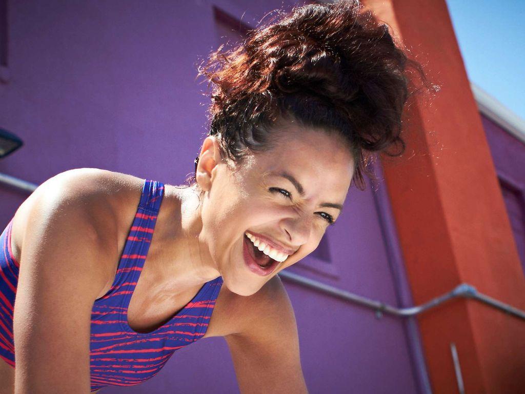 Sport und Gehirn: Junge Frau lacht beim Sporttraining.