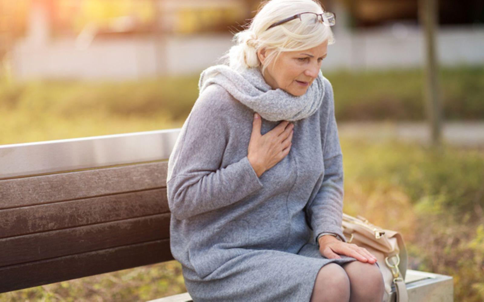 Lungenembolie: Ältere Dame sitzt auf einer Parkbank und ringt nach Luft