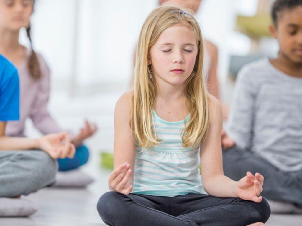 Achtsamkeit: Eine Gruppe Kinder sitzt auf dem Boden und meditiert.