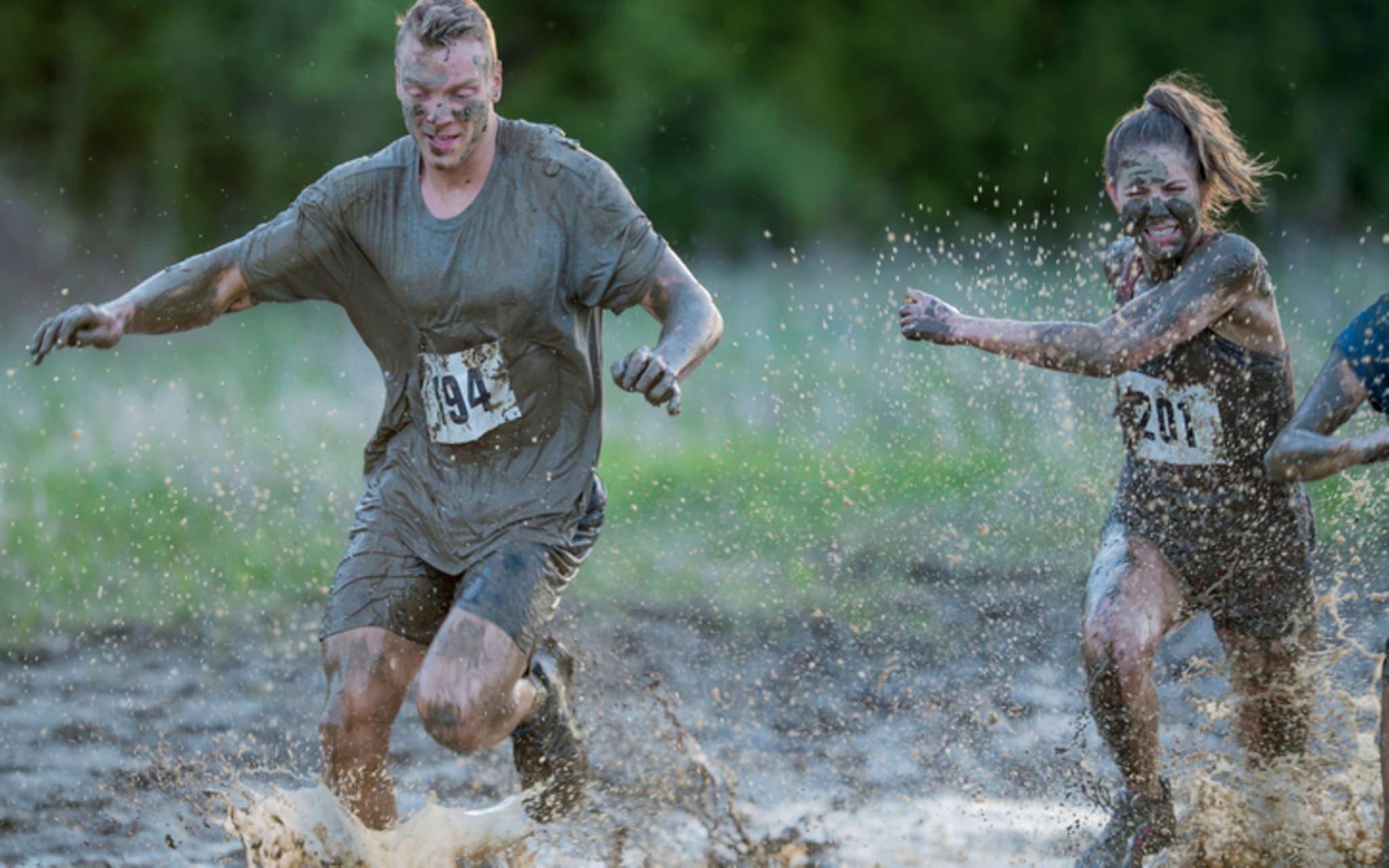 Matschläufe: Ein Mann und eine Frau laufen durch Matsch und Wasser.