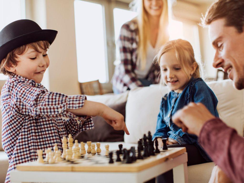 Schach fürs Gehirn: Zwei Kinder spielen mit ihrem Vater Schach.