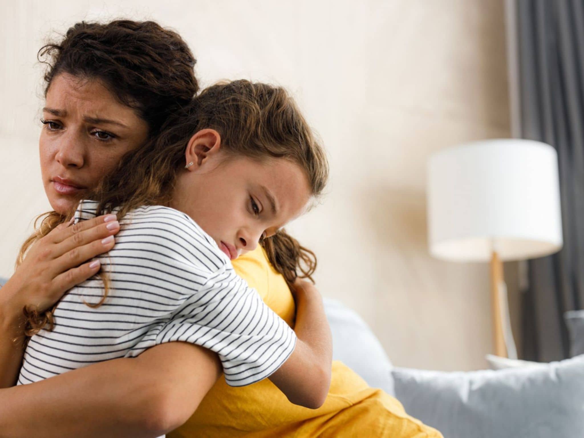Die junge besorgte Mutter tröstete ihr depressives kleines Mädchen im Wohnzimmer.