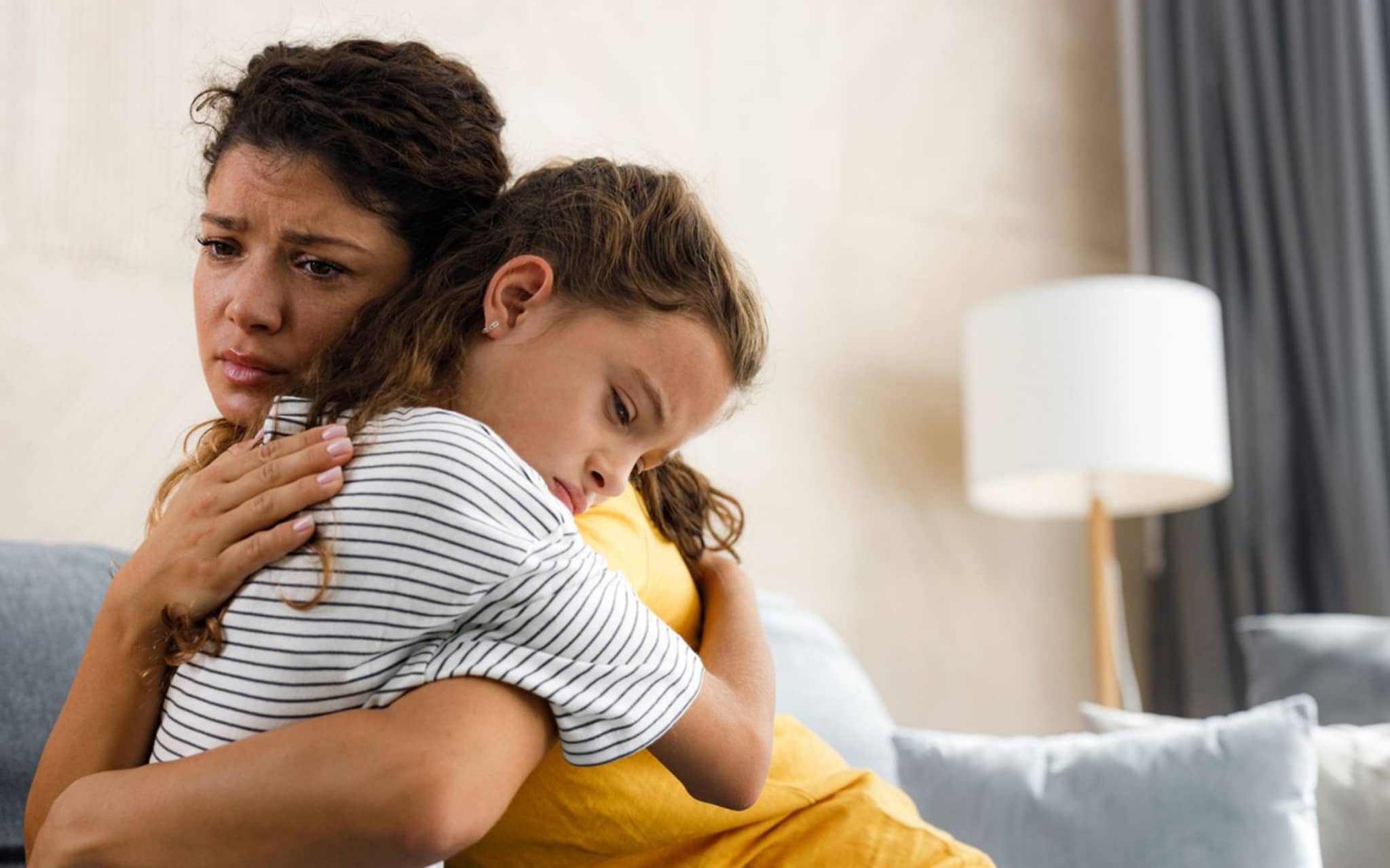 Die junge besorgte Mutter tröstete ihr depressives kleines Mädchen im Wohnzimmer.