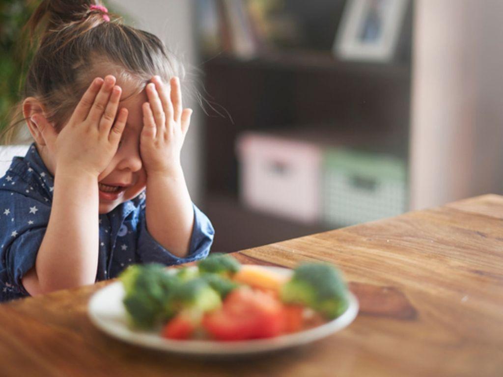 Essensverweigerung: Ein kleines Mädchen sitzt vor seinem Teller und möchte nicht essen