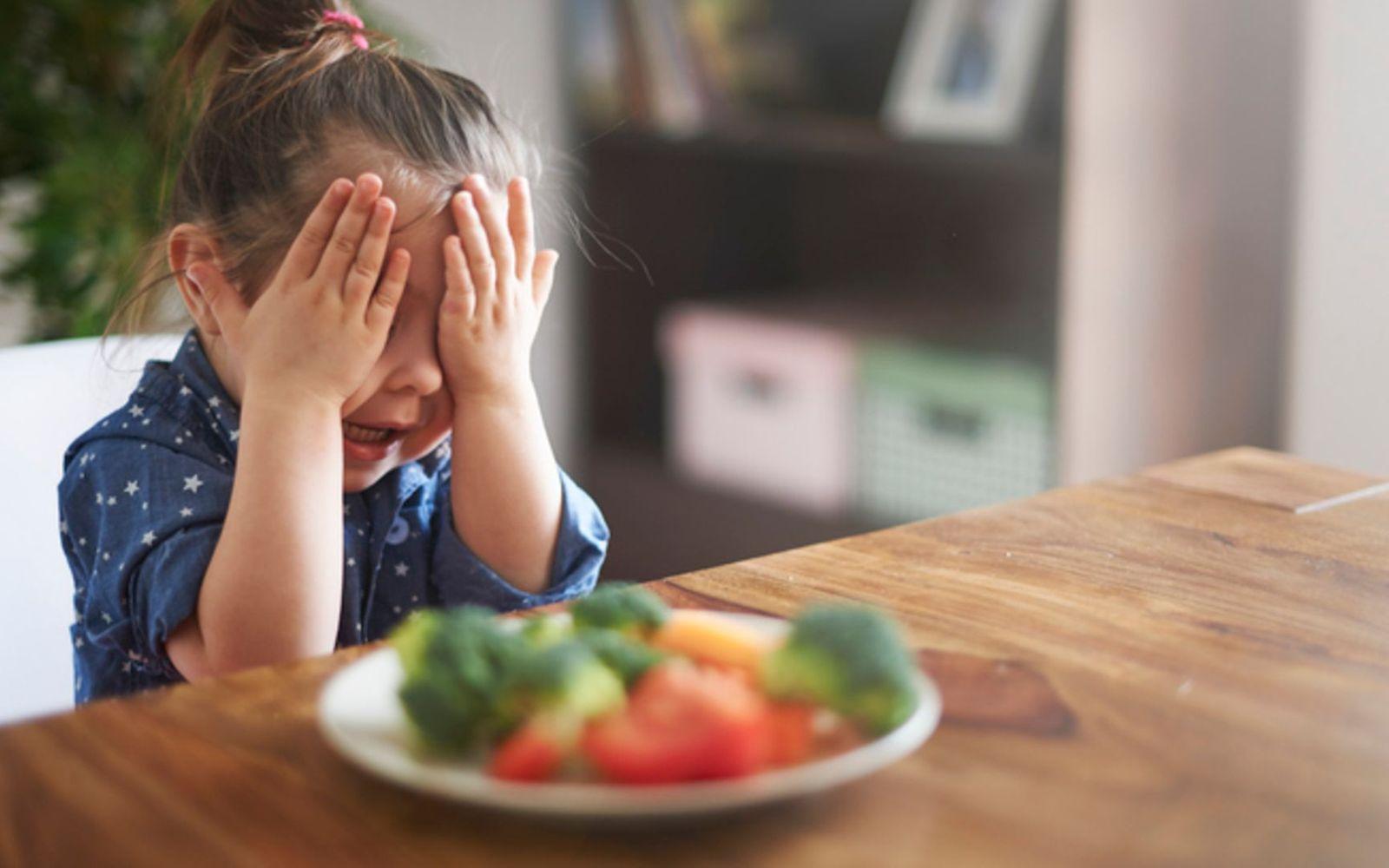 Essensverweigerung: Ein kleines Mädchen sitzt vor seinem Teller und möchte nicht essen