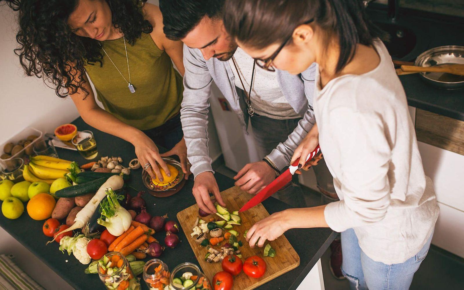 Sekundäre Pflanzenstoffe: Eine Gruppe von Freunden bereitet in der Küche vegetarisches Essen zu.