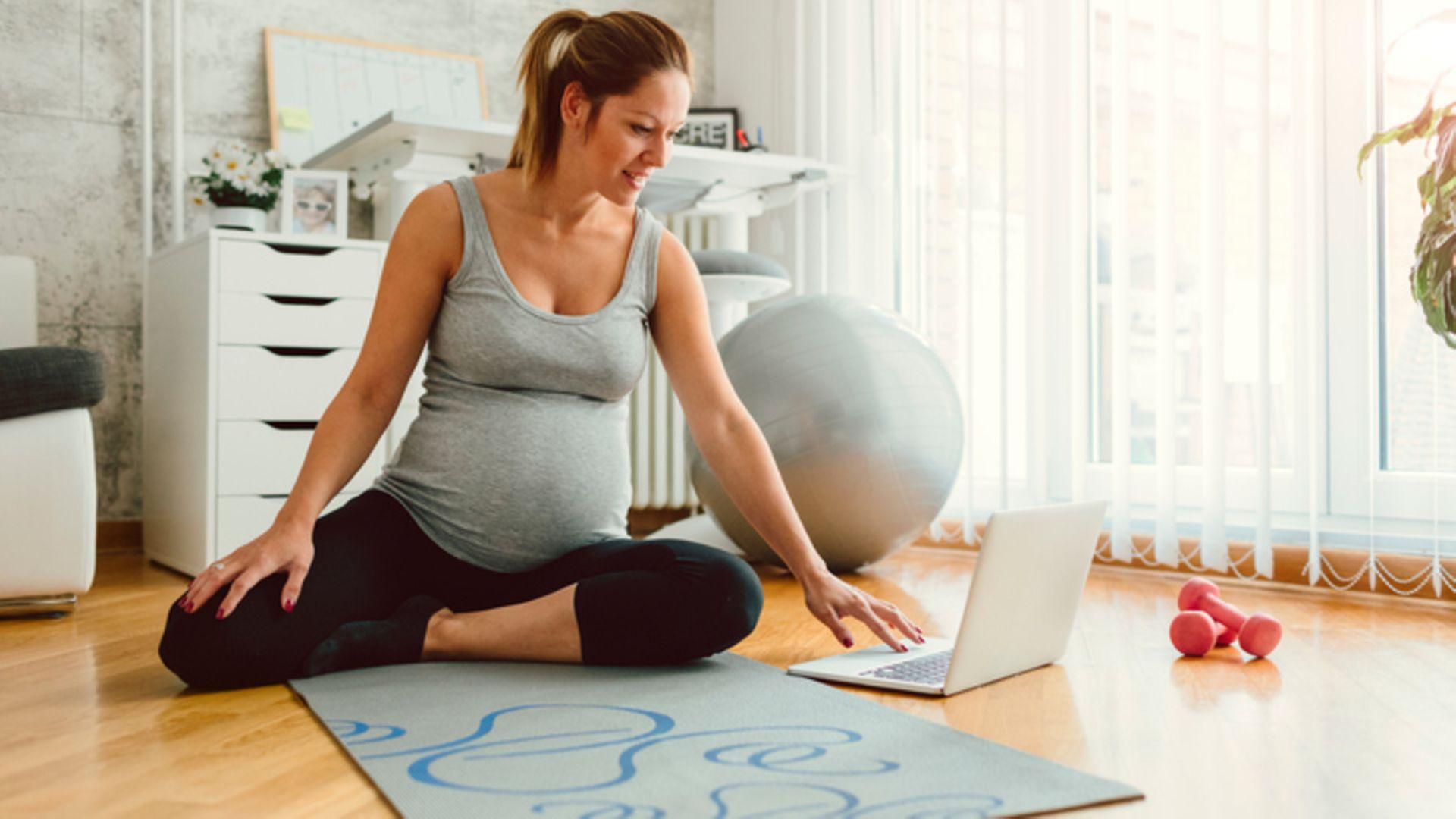 Sport in der Schwangerschaft: Eine hochschwangere Frau macht Gymnastik per Online-Training