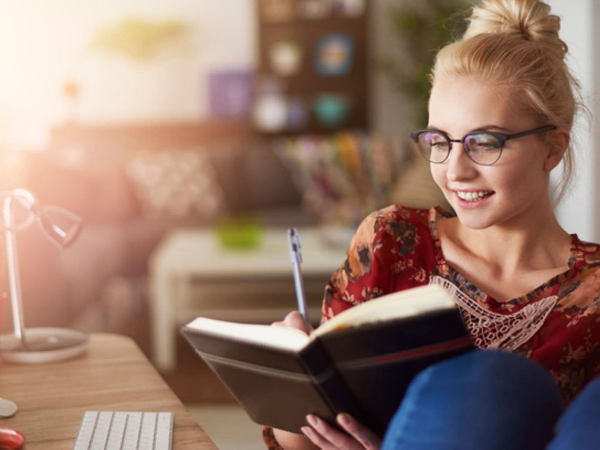 Neujahrsvorsätze: Eine junge Frau schreibt was in ein Notizbuch.