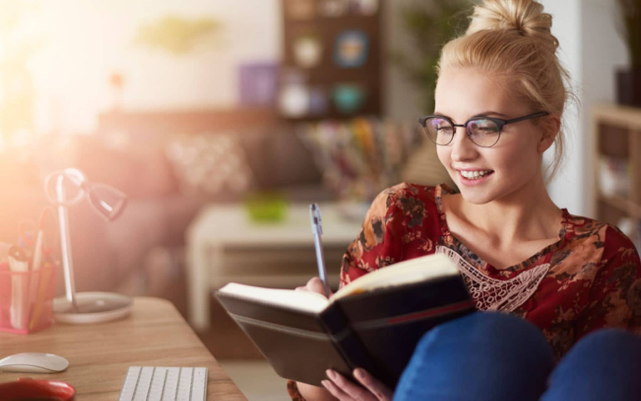Neujahrsvorsätze: Eine junge Frau schreibt was in ein Notizbuch.