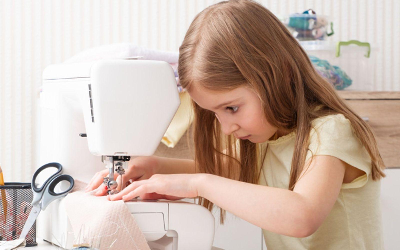 Symbolbild Nähen mit Kindern: Ein Mädchen näht mit einer Nähmaschine
