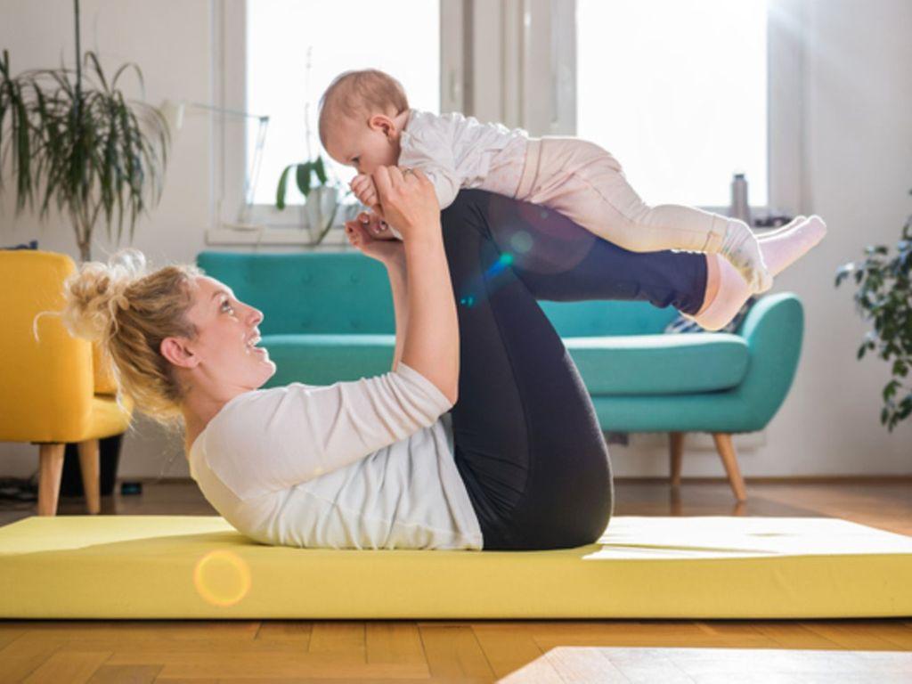 Sport nach der Schwangerschaft: Eine Mutter macht Gymnastik mit ihrem Baby