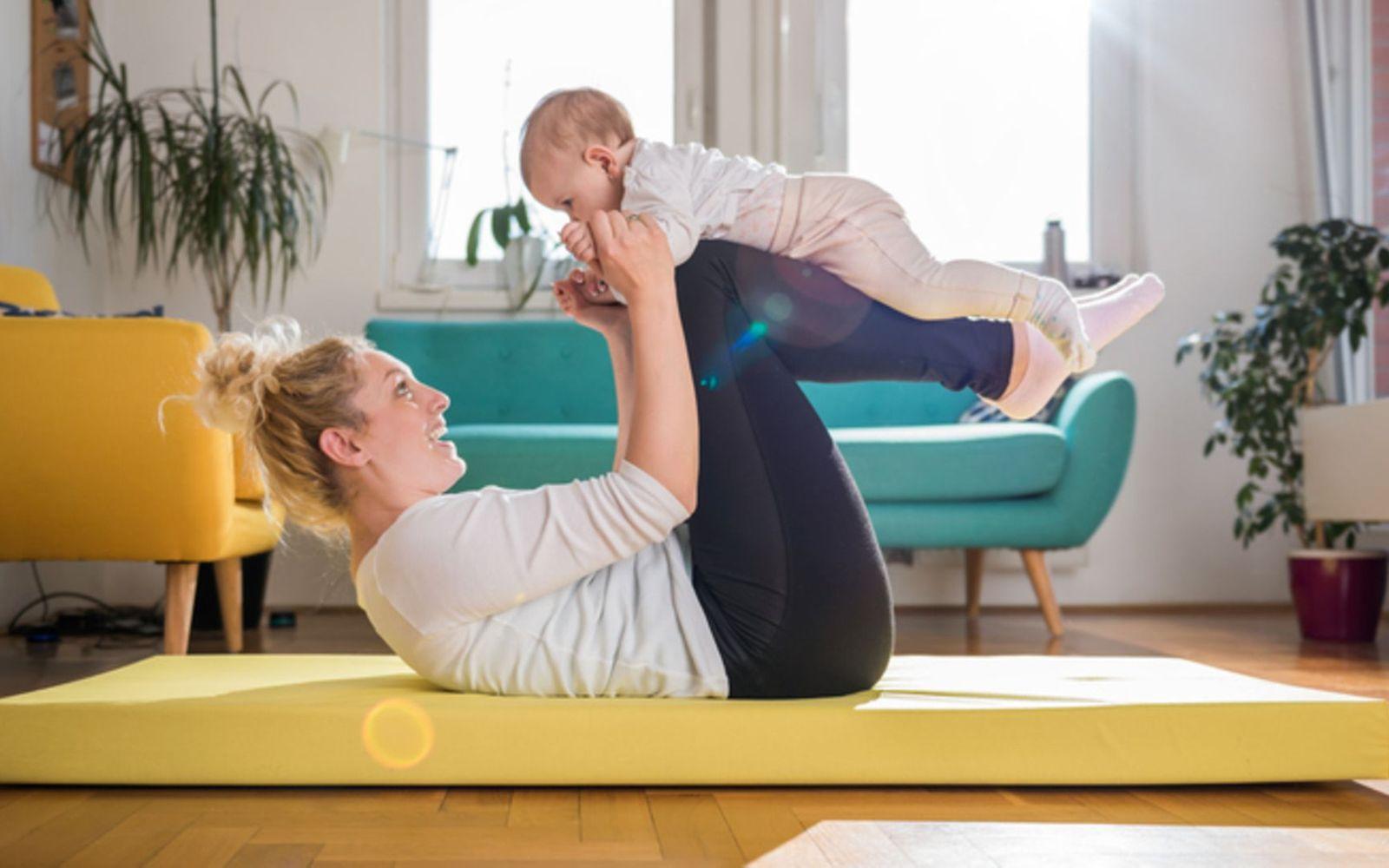 Sport nach der Schwangerschaft: Eine Mutter macht Gymnastik mit ihrem Baby