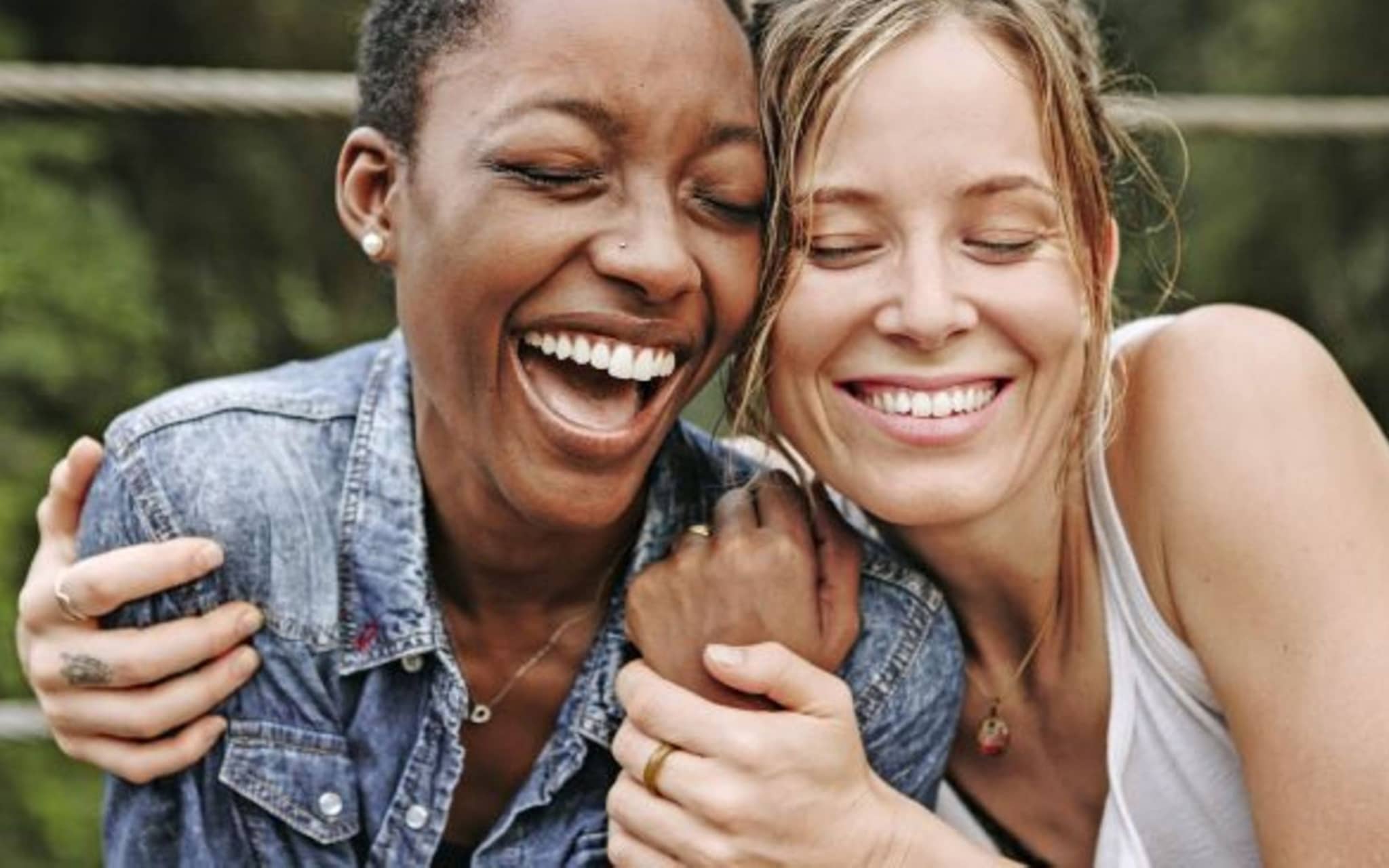 Zwei Frauen, die sich in den Arm nehmen und gemeinsam lachen.