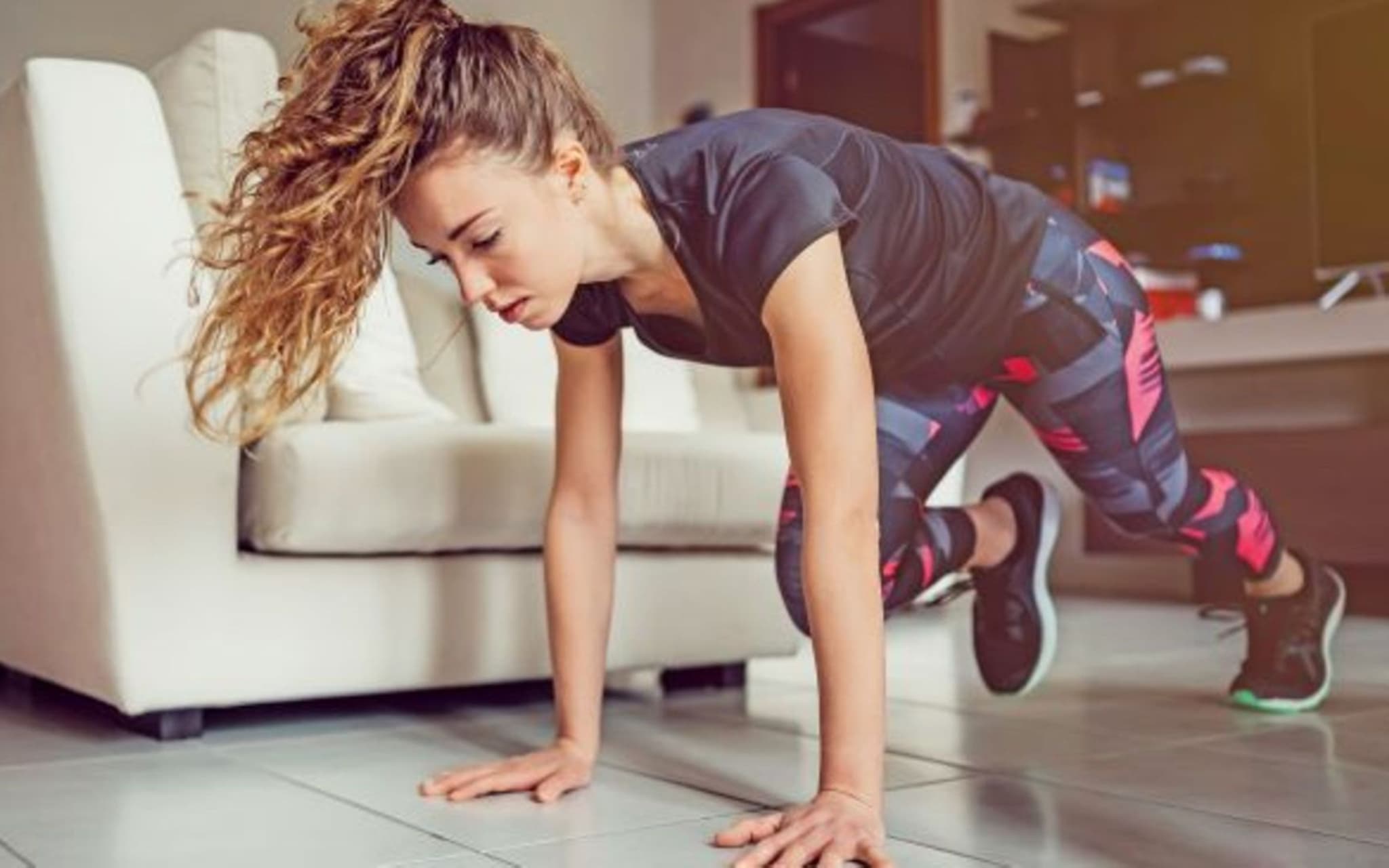 Symbolfoto für Fit im Homeoffice: Eine Frau macht zuhause Gymnastik
