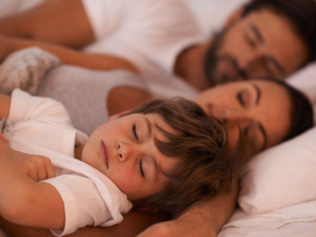 Symbolbild für Co-Sleeping: Ein Kind schläft mit im Bett seiner Eltern